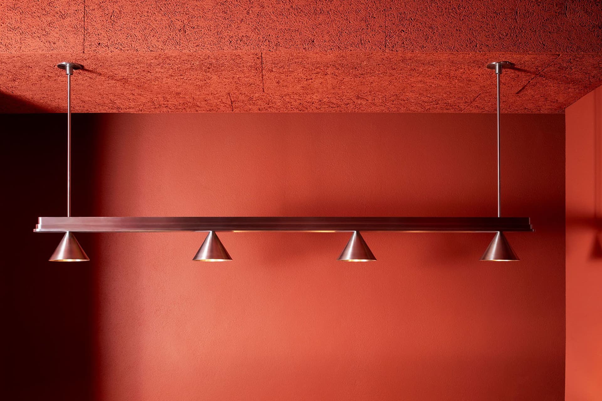 A warm and inviting room with an orange wall, brick texture, and soft lighting from hanging silver fixtures