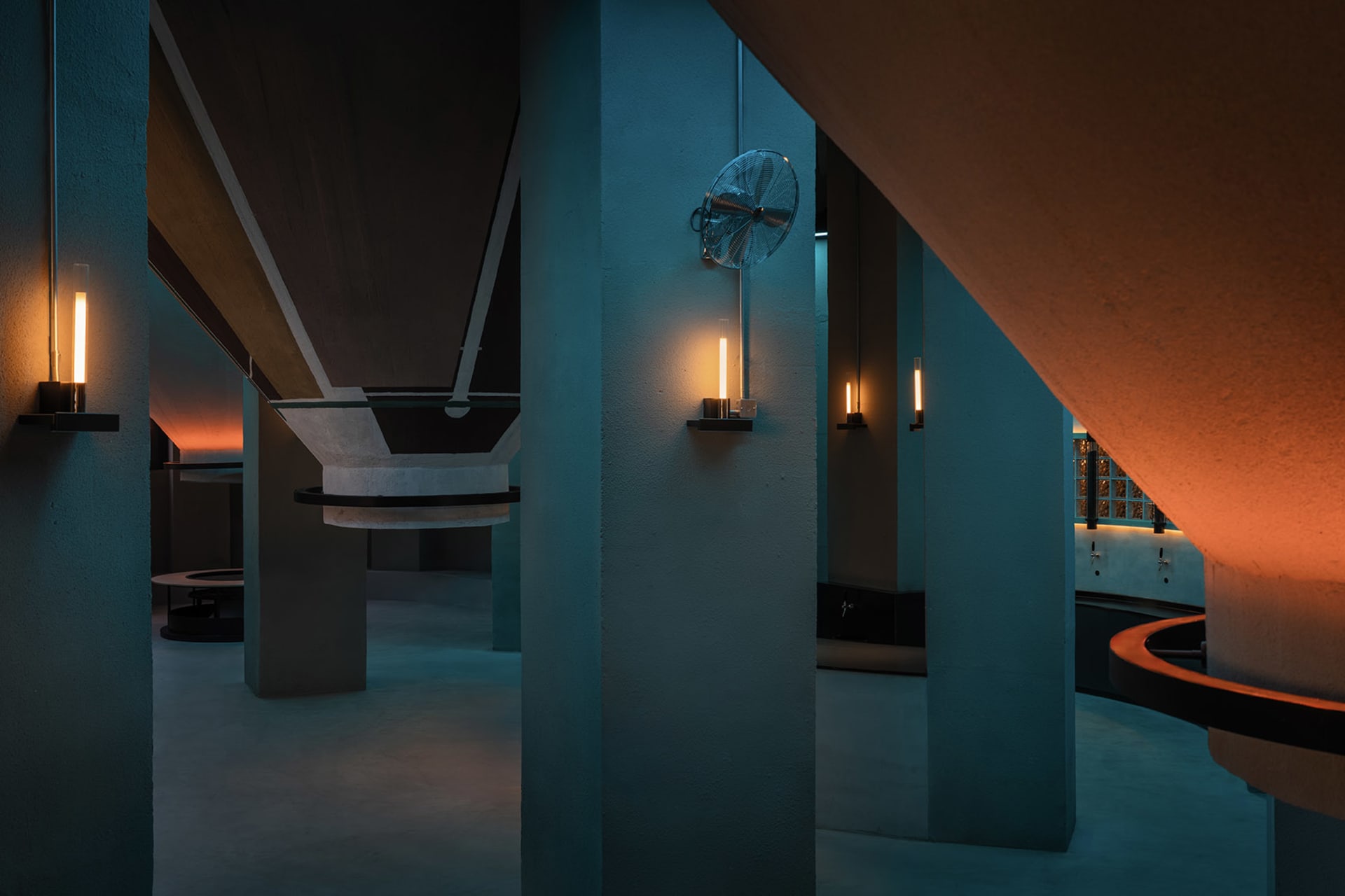 A dimly lit industrial space with concrete pillars and walls, creating a mysterious atmosphere