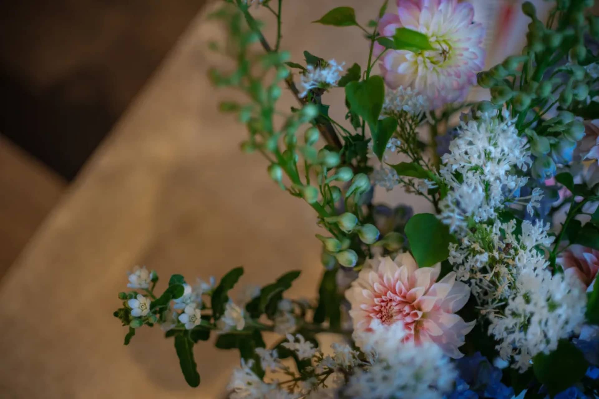 A bouquet of pink and white flowers in a vase on a table, creating a visually appealing display with a warm and inviting atmosphere