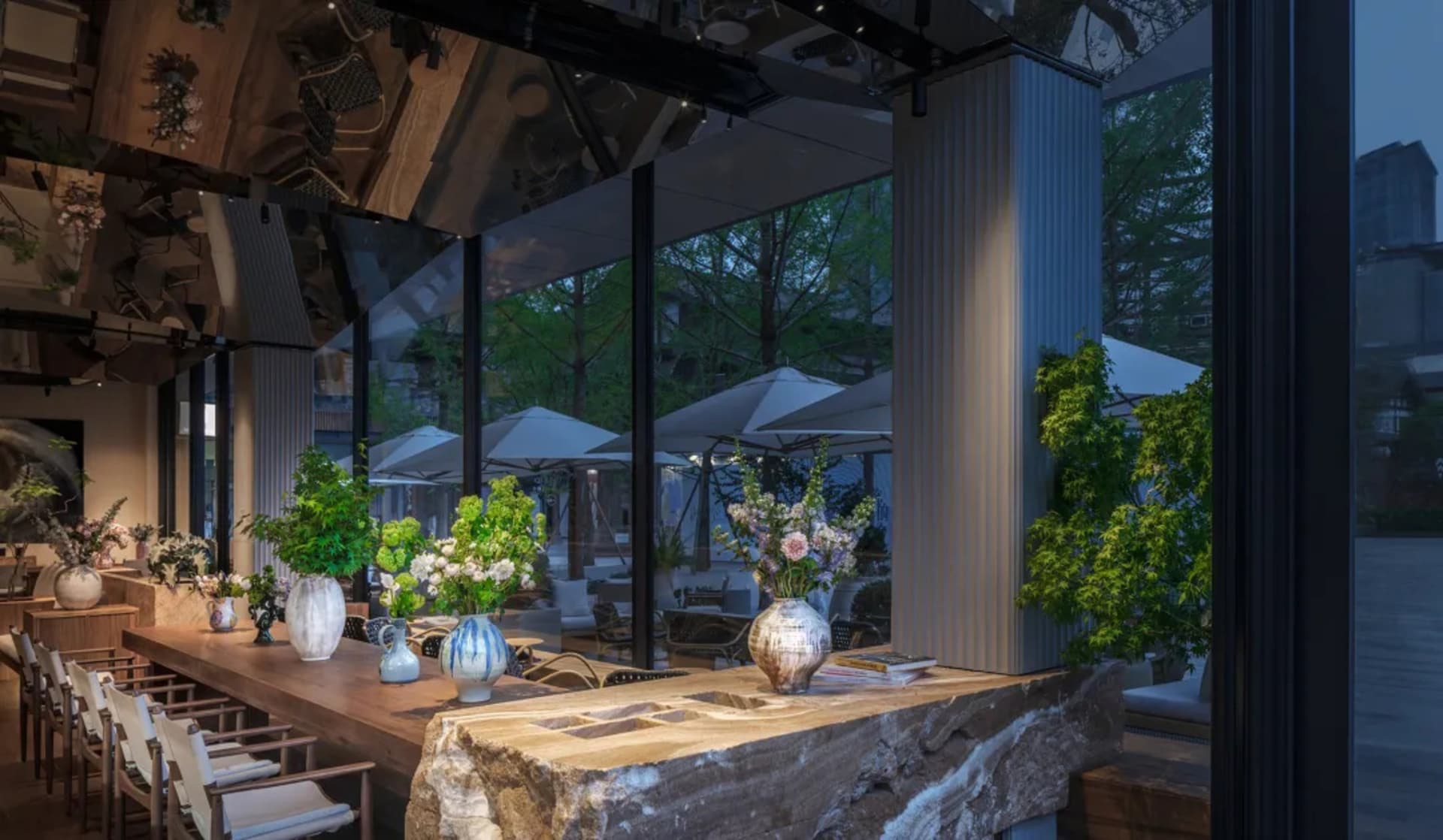 Elegant dining space with a stone countertop, vases, umbrellas, and natural elements, designed for socializing or dining