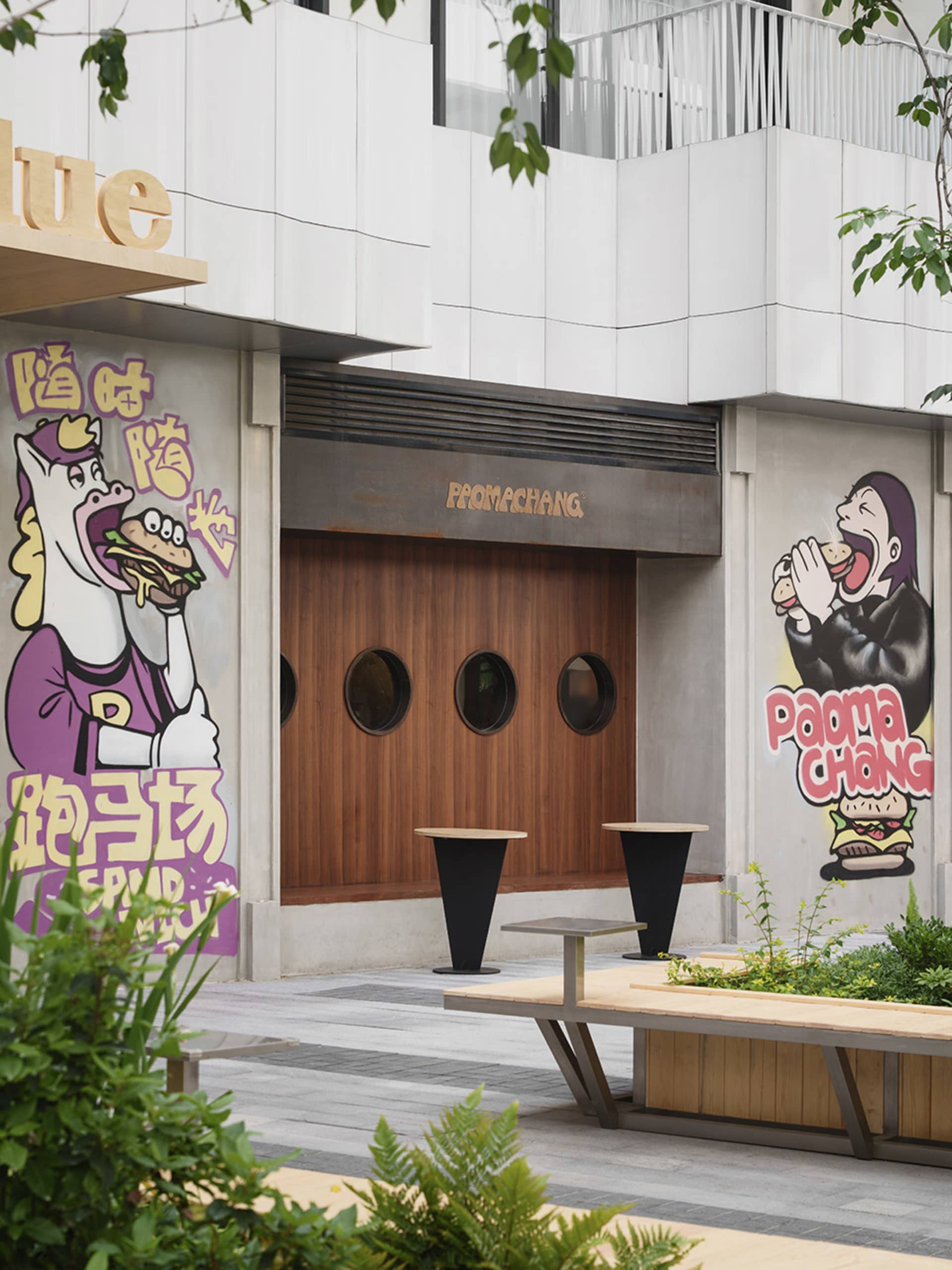 A modern Asian restaurant with a horse statue eating a sandwich, wood and concrete elements, and various artworks on the walls, creating a warm and inviting atmosphere