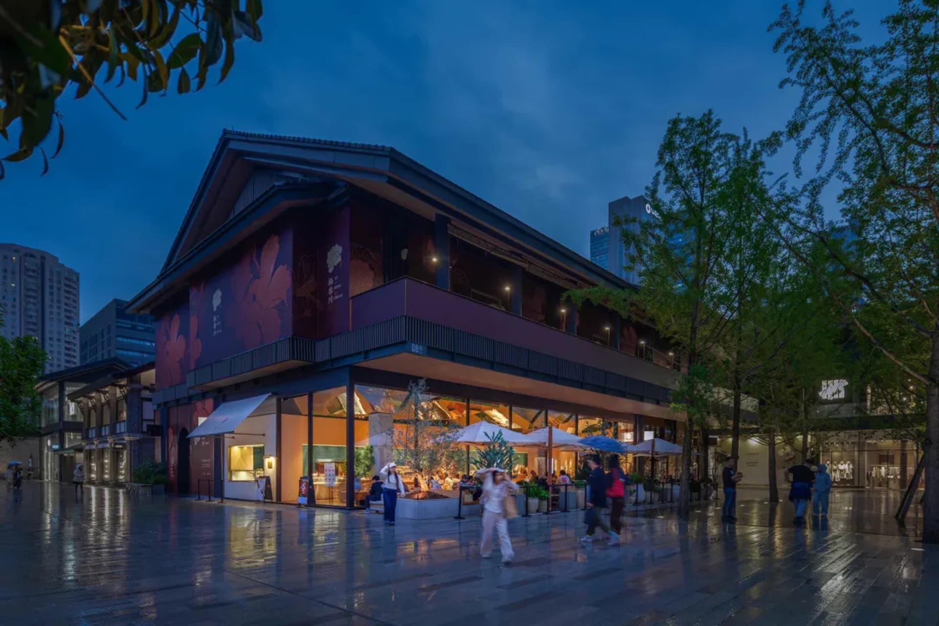 Modern Asian restaurant with a large dining area, wooden flooring, metal accents, and umbrellas providing shade to tables