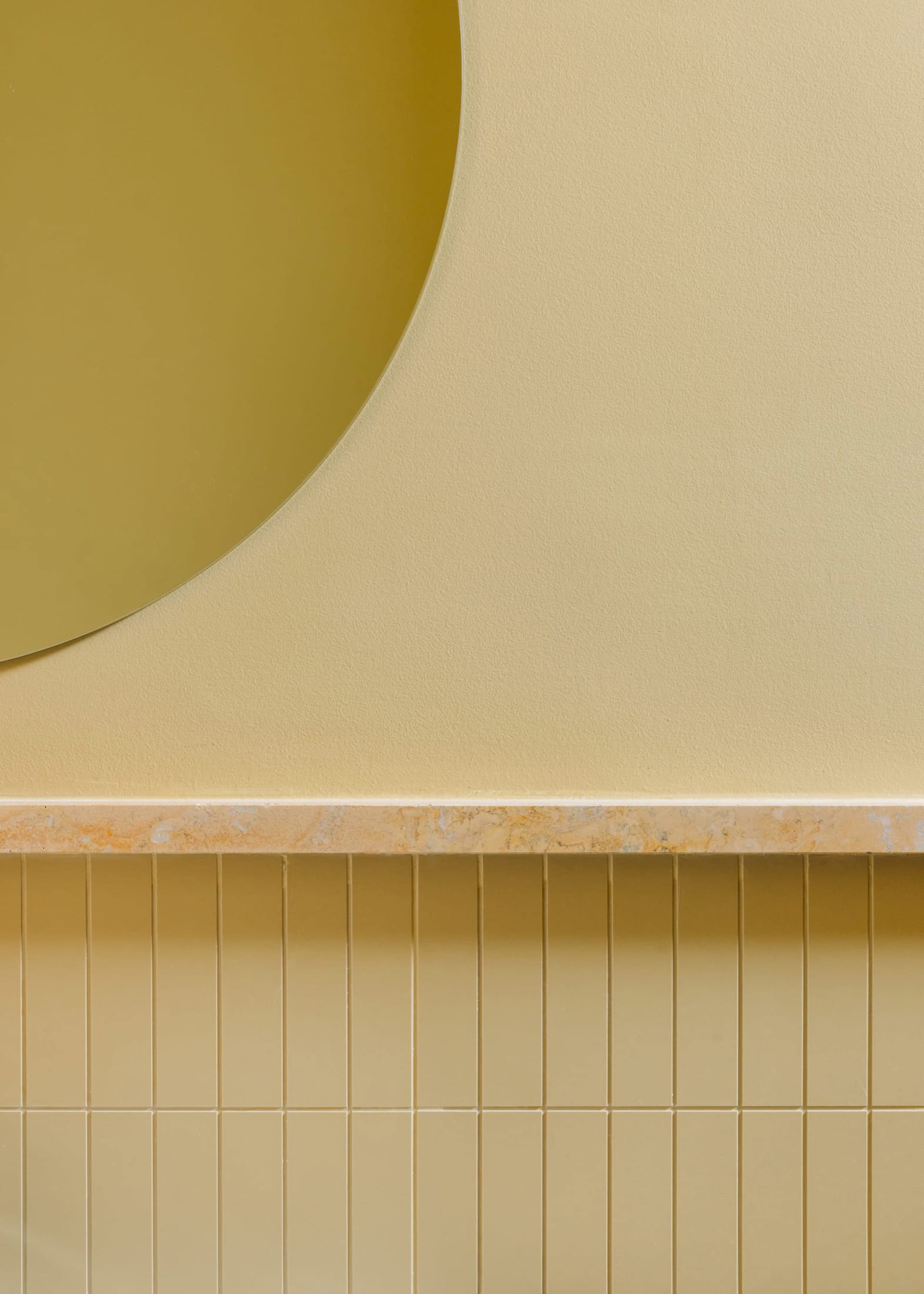 Bright and inviting interior space with yellow walls, a large round mirror, and two smaller mirrors creating a sense of depth