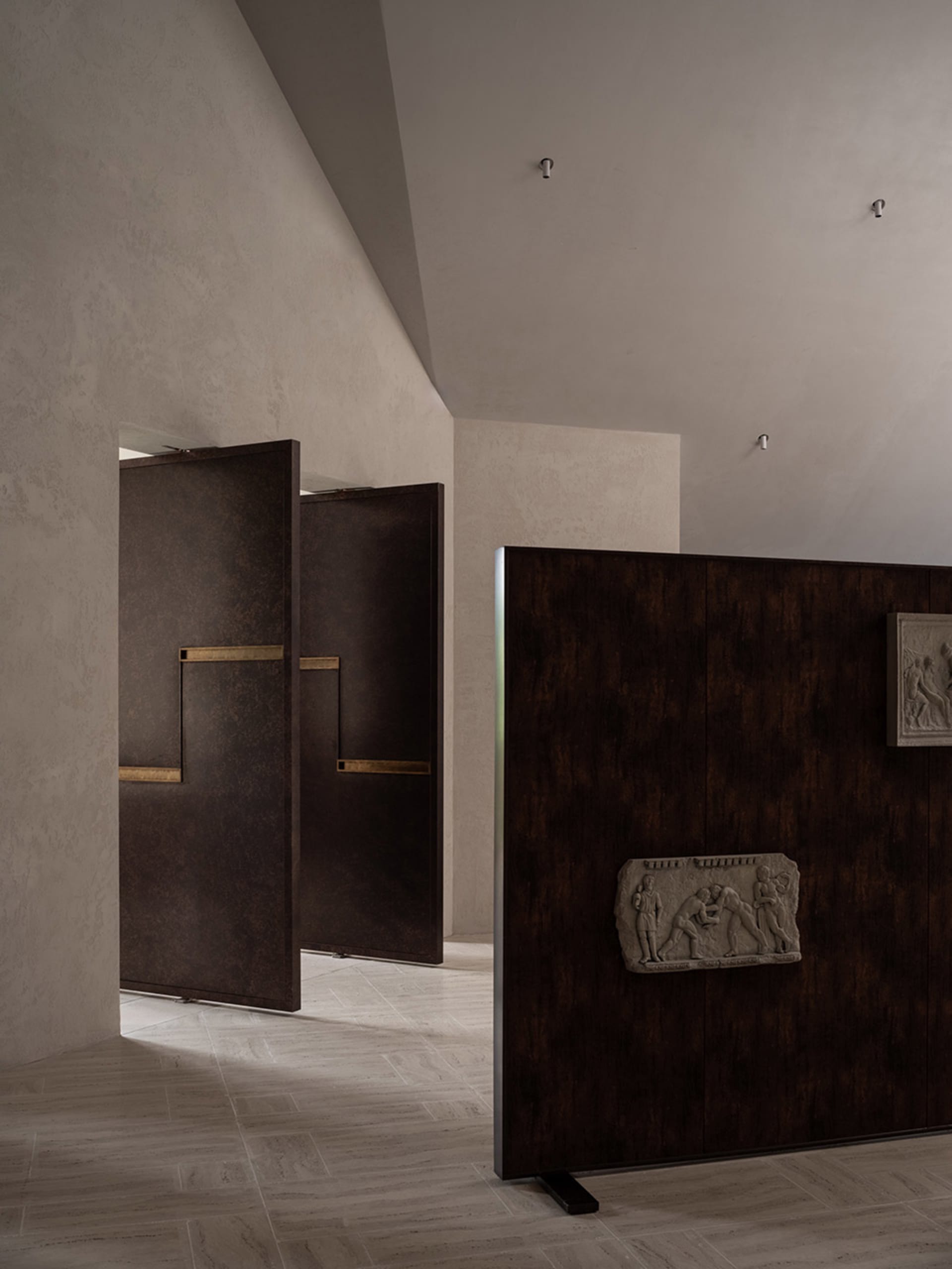 A clean and minimalist hallway with two open doors, one brown wood door and one darker door, set against a wooden floor