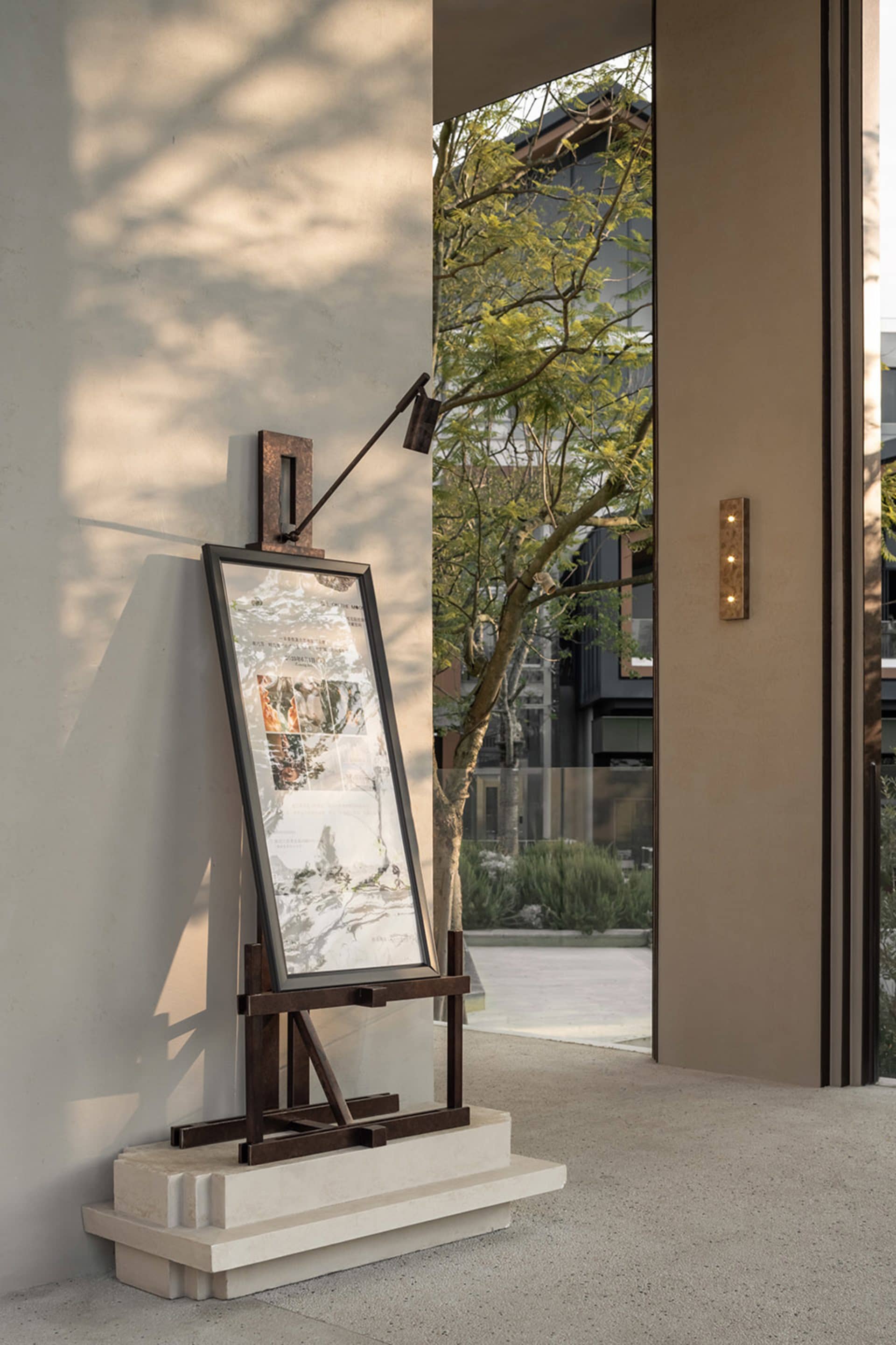 A framed artwork on a wooden stand in front of a building, adding a creative touch to the urban environment