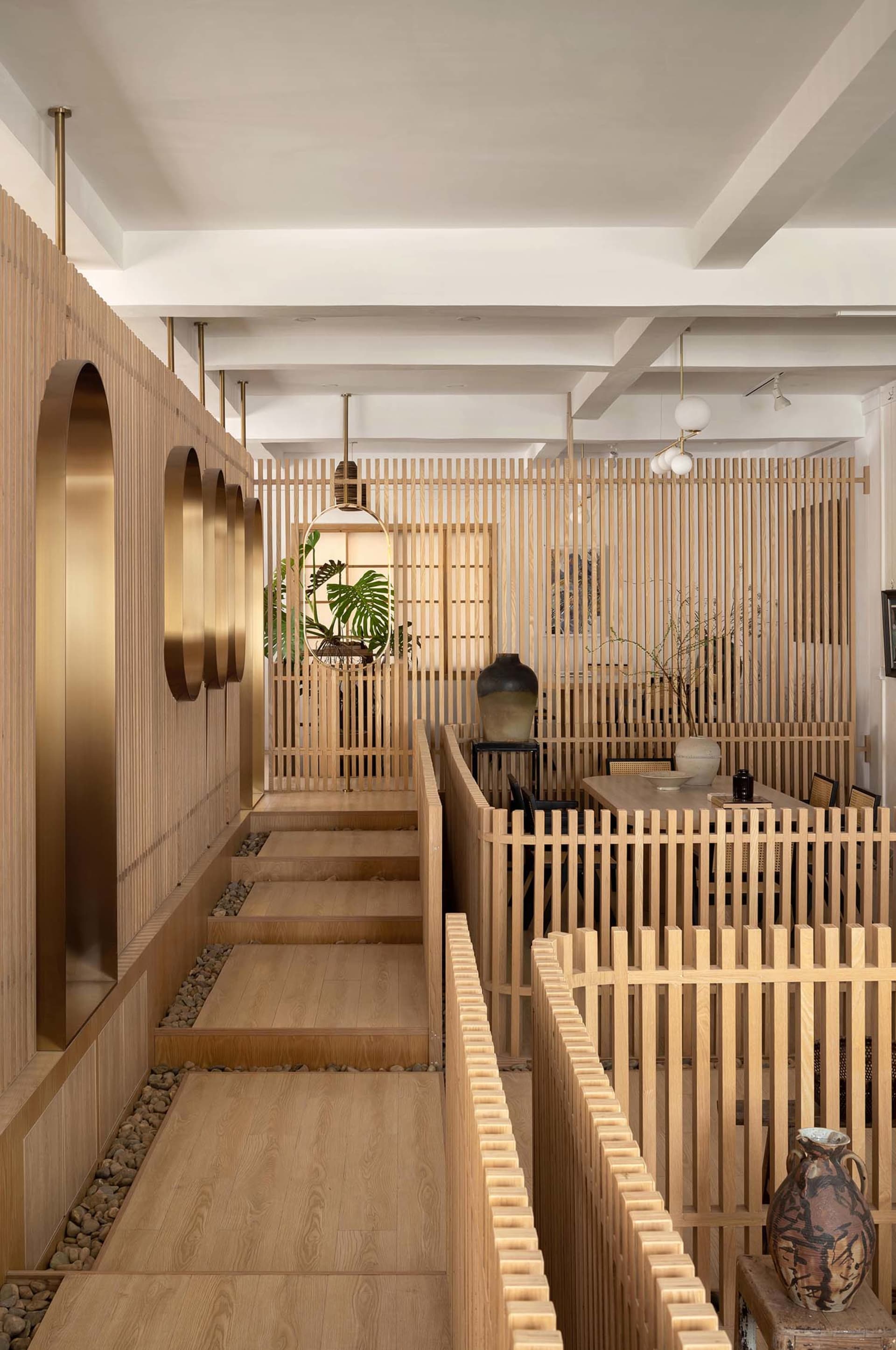 Warm and inviting home interior with wooden walls and floors, featuring a dining area, living room, and steps leading to another level, with natural elements and potted plants