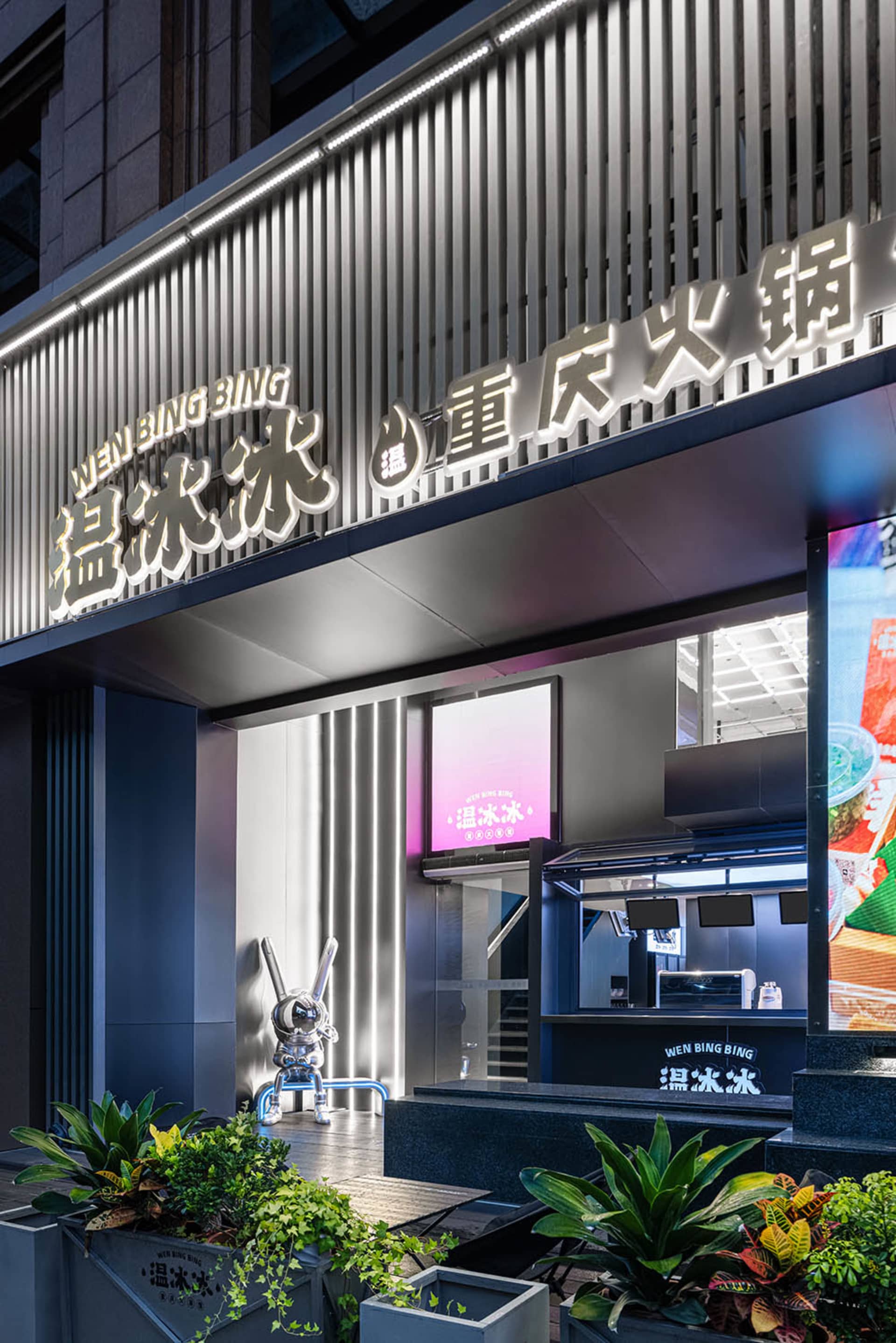 A modern Asian restaurant with a black countertop, natural light, and TV screens on the walls