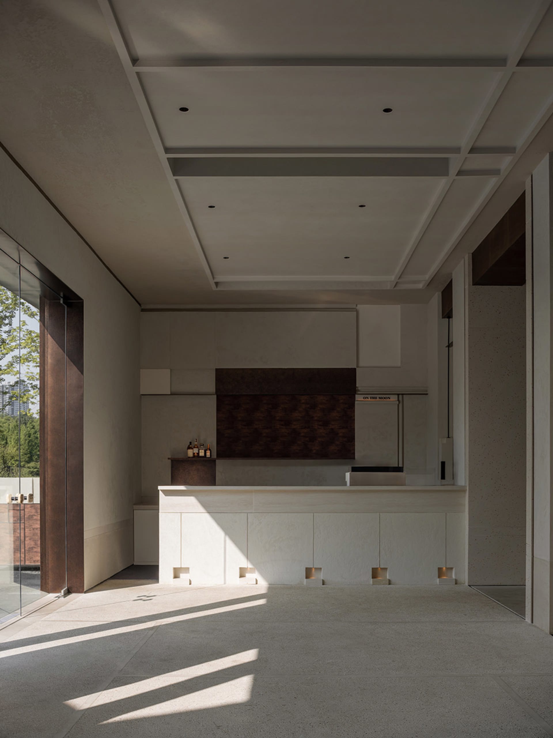 Modern kitchen with white countertops and cabinets, two sinks, and three bottles on the countertops