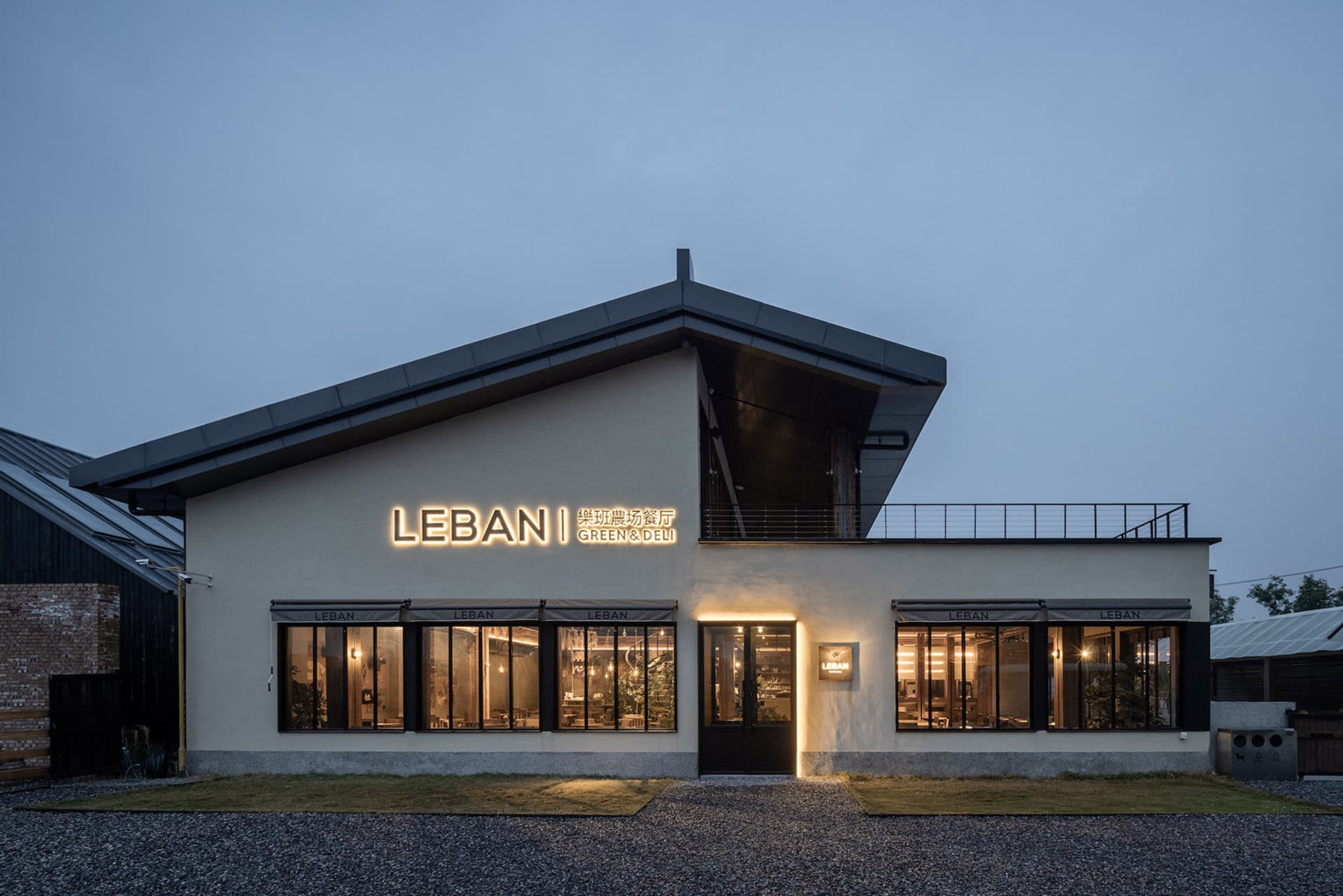 A modern building with a concrete facade, large windows, and a sign reading Lebani, set against a clear blue sky