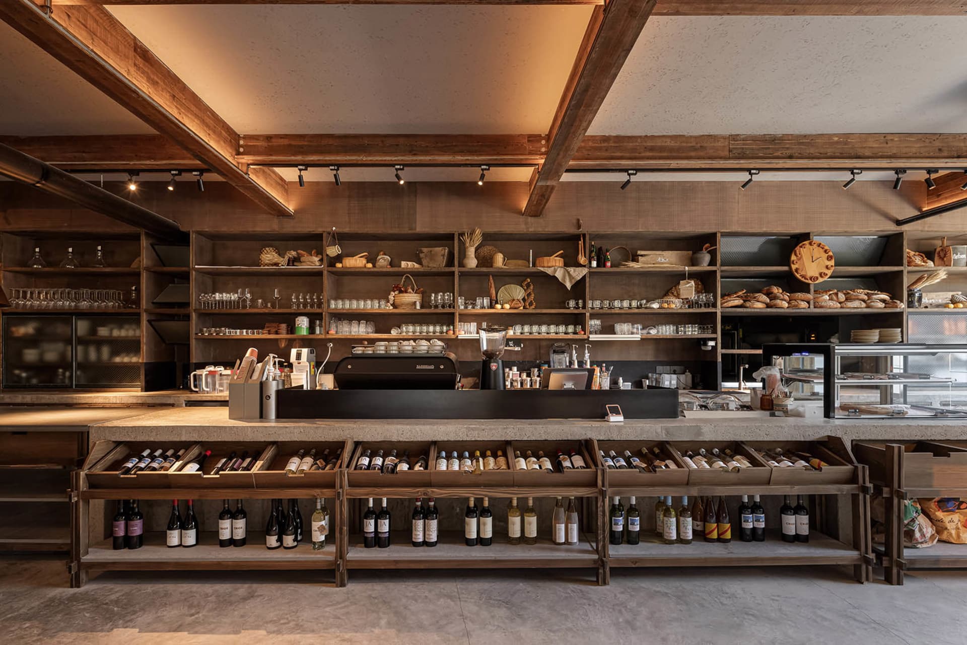 一間井然有序的葡萄酒商店，展示架上陳列各式酒瓶與杯具，為顧客營造溫馨邀約的氛圍