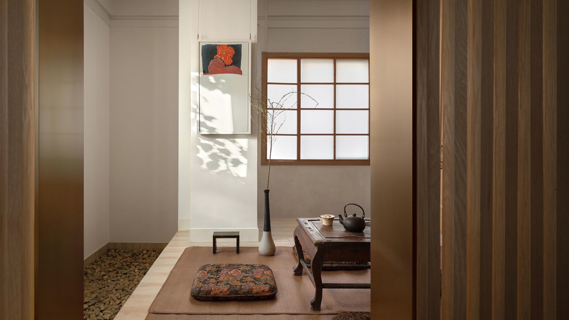 Cozy living space with hardwood floor, white walls, two couches, a chair, a vase, and a bowl, with a warm and inviting atmosphere