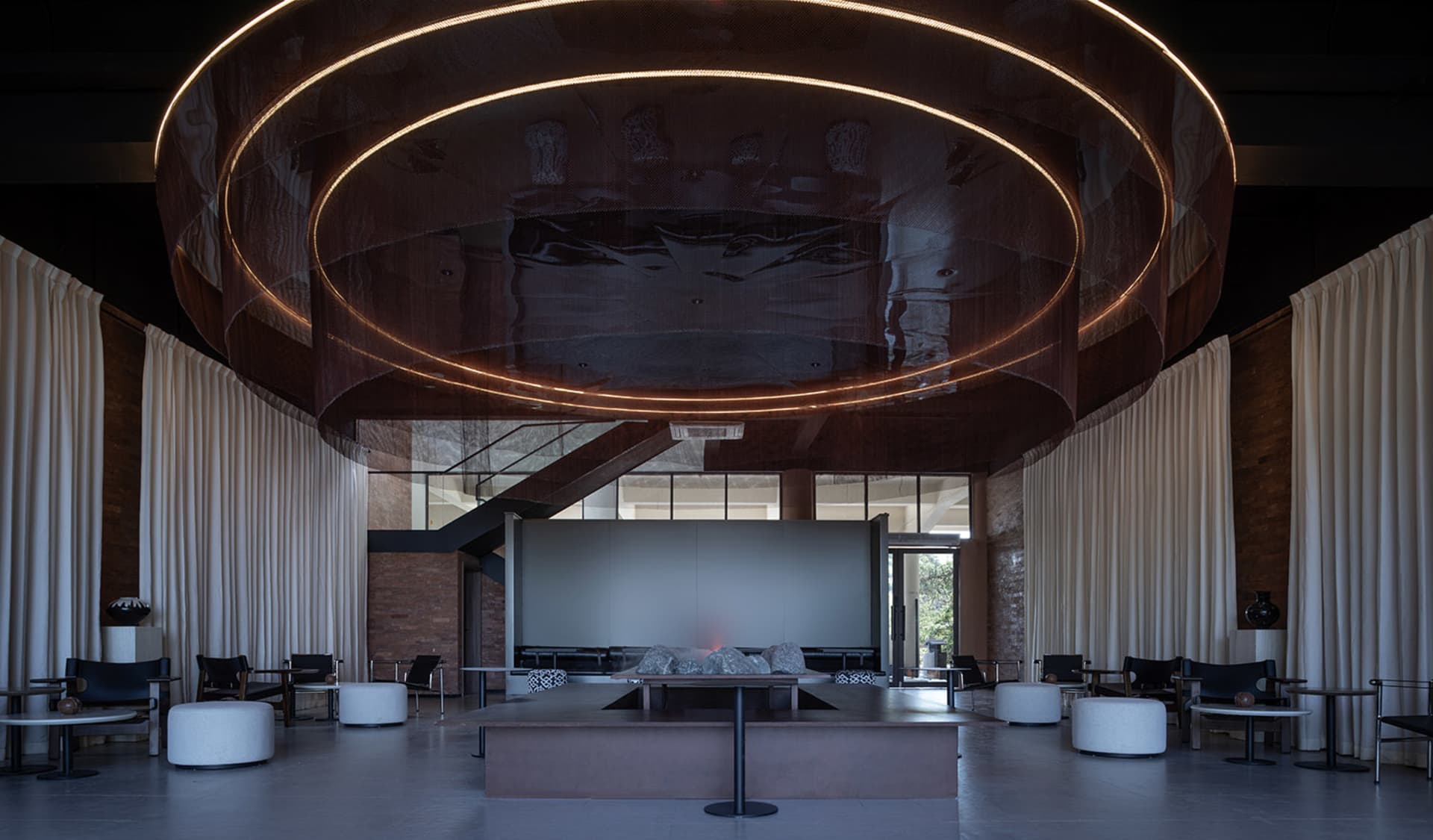 Elegant hotel lobby with a large circular table, multiple couches, and a wooden ceiling