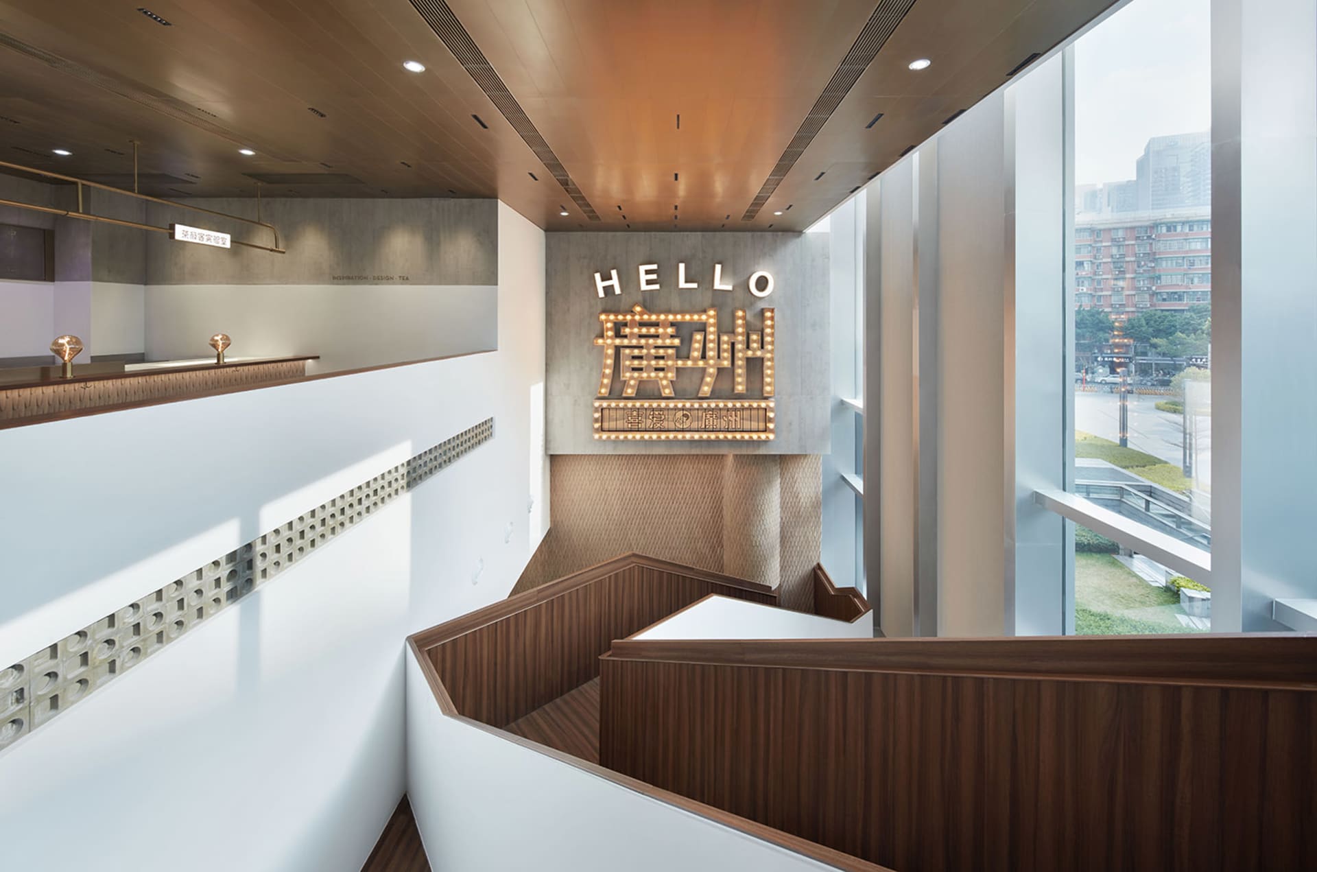 A modern staircase with wooden steps and a brown tint, featuring a large sign reading 'hello' above the steps in a welcoming atmosphere