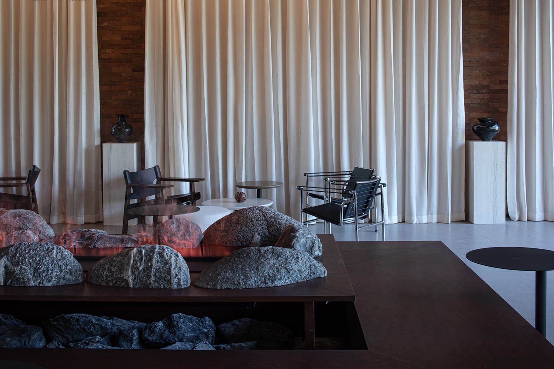 A modern living space with a stone fireplace, comfortable seating, and a dining table, featuring natural materials and a warm atmosphere