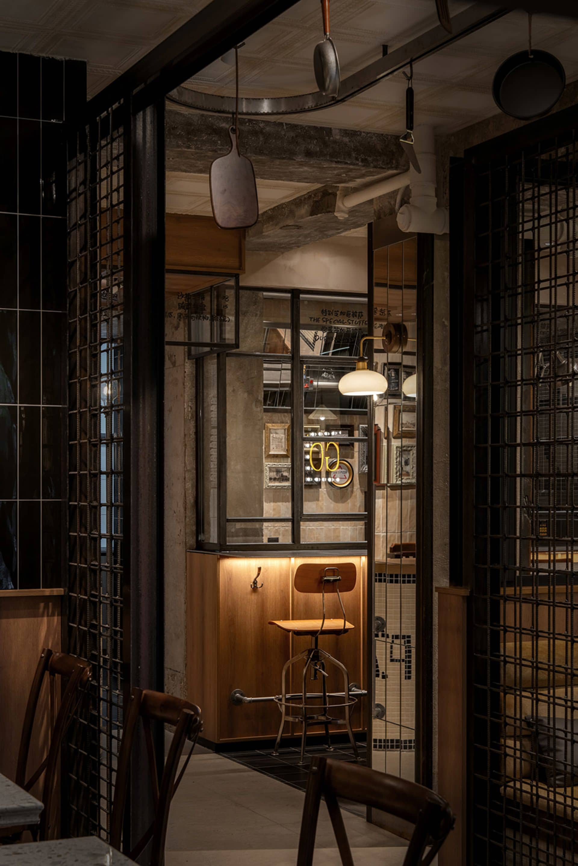 Dimly lit casual dining area with a dining table and chairs, surrounded by tile walls and additional tables in the background