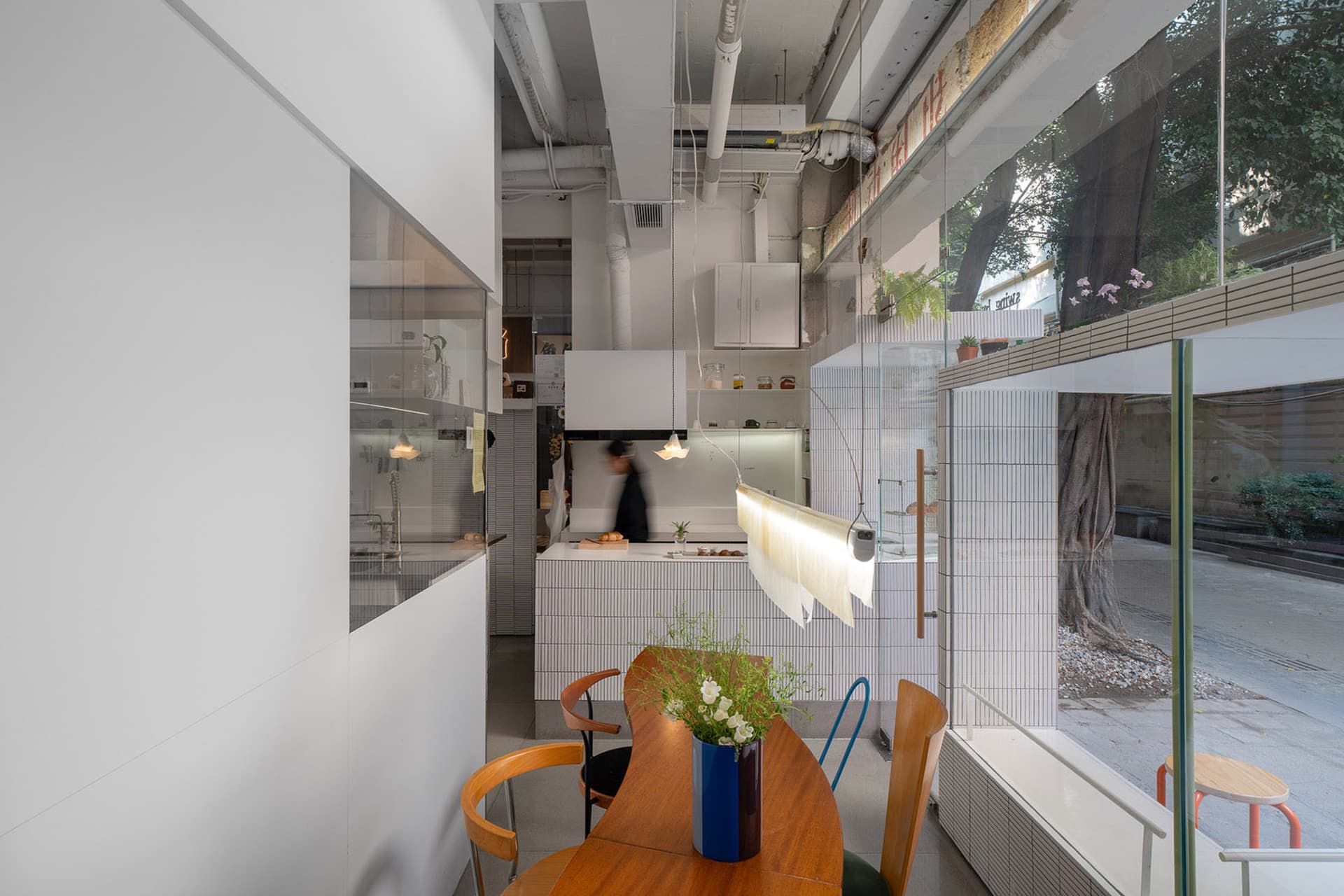Open kitchen with white walls, wooden floors, a dining table, chairs, and kitchen appliances