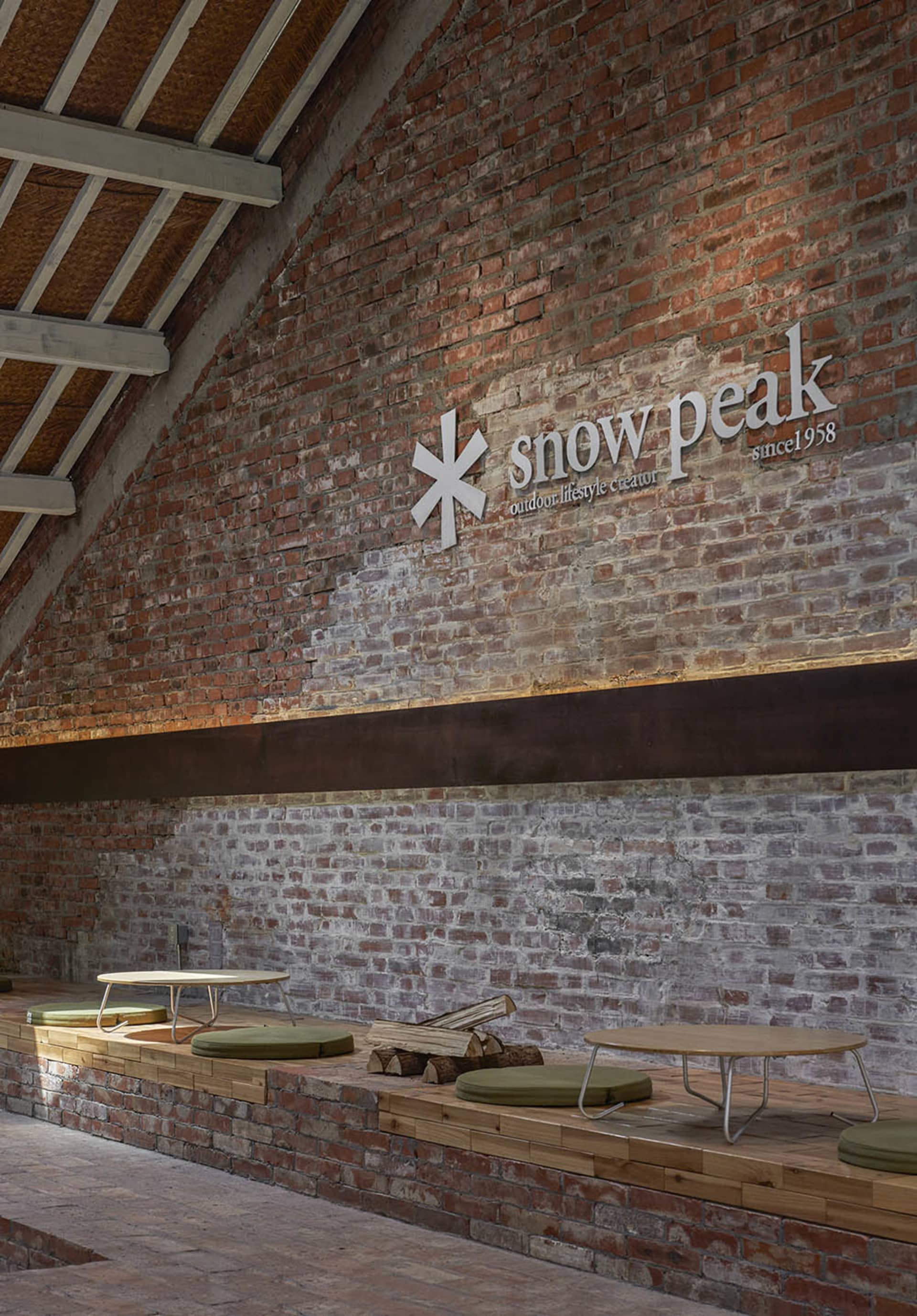 Cozy indoor space with a brick wall, wooden table, and chairs, creating a warm and inviting atmosphere