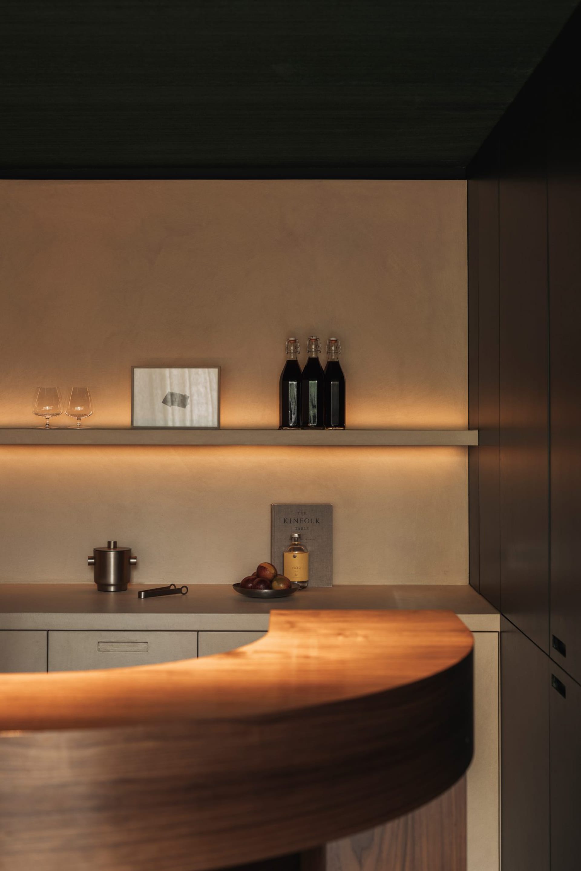 Warm and inviting kitchen with a wooden countertop, cabinets, and a bottle of wine, accompanied by two wine glasses and three apples