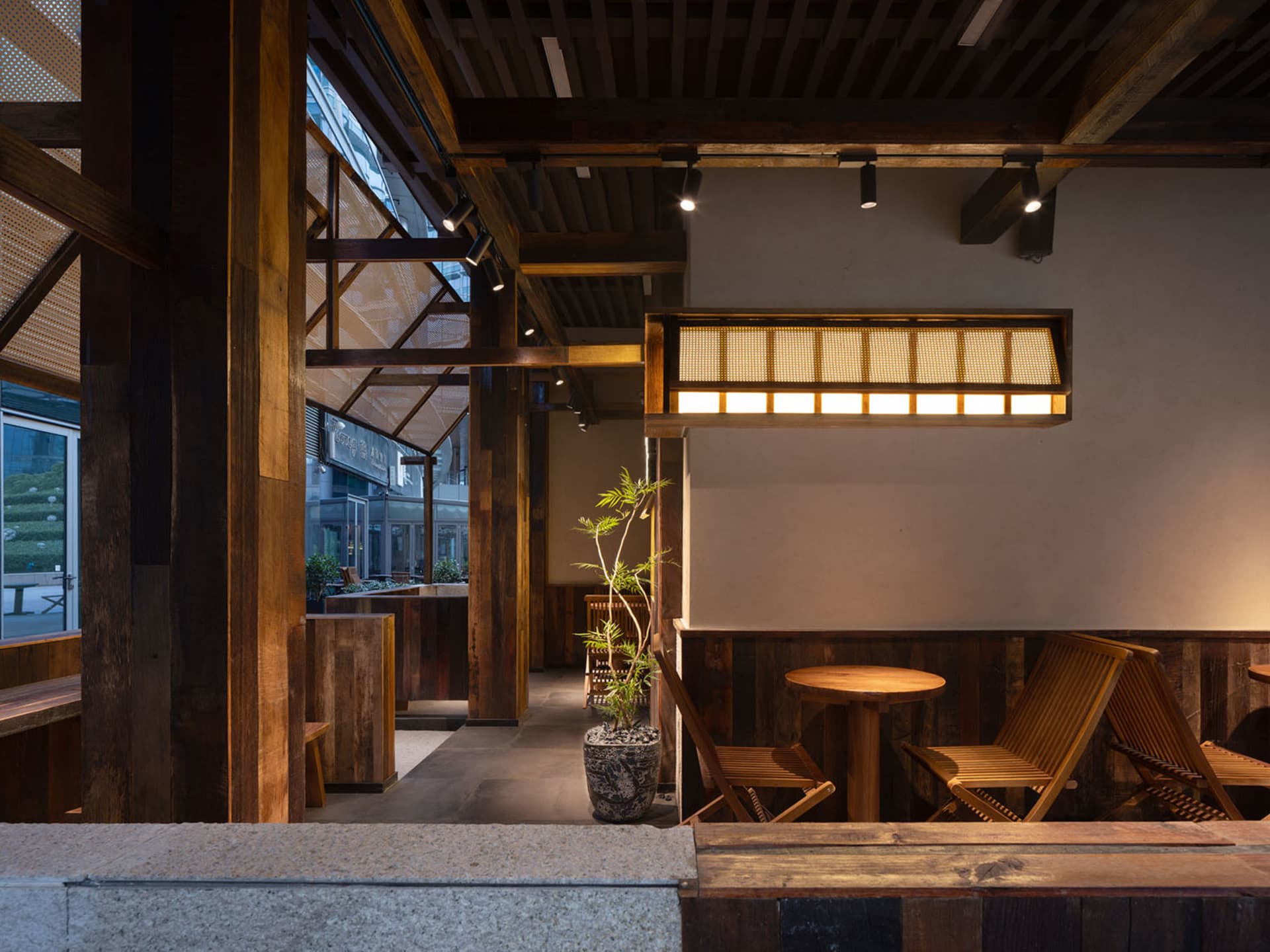 Cozy restaurant interior with wooden walls, chairs, and a potted plant, creating a warm and inviting atmosphere