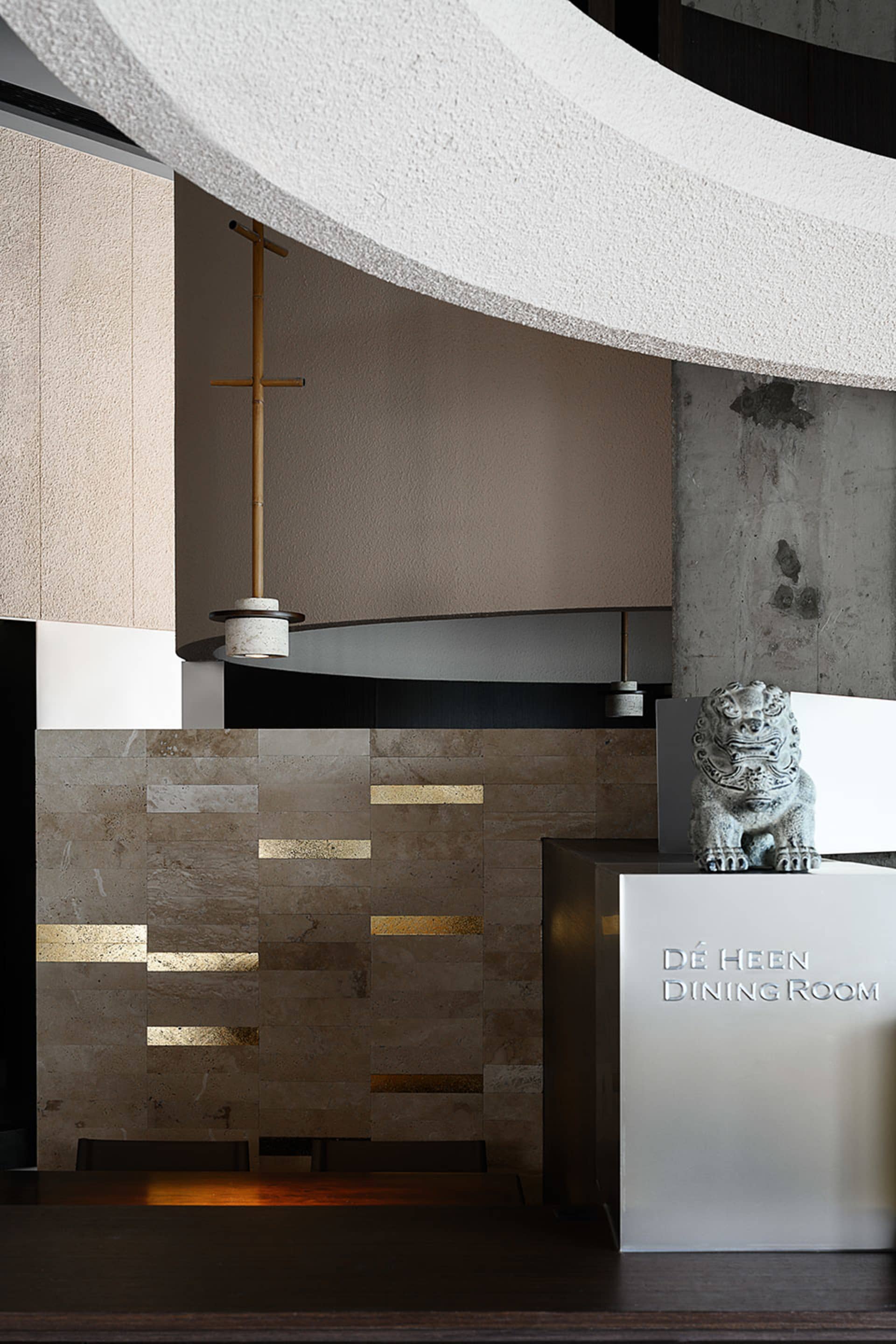 Dining room with a large stone wall, two statues, a fireplace, and a modern interior design