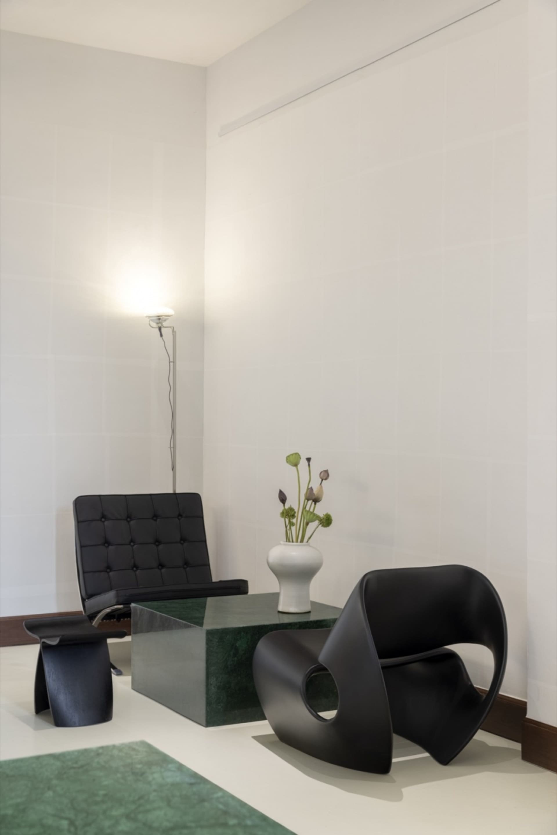 A modern living space with a leather chair in front of a glass table, surrounded by vases and a potted plant, with a clean and minimalistic atmosphere