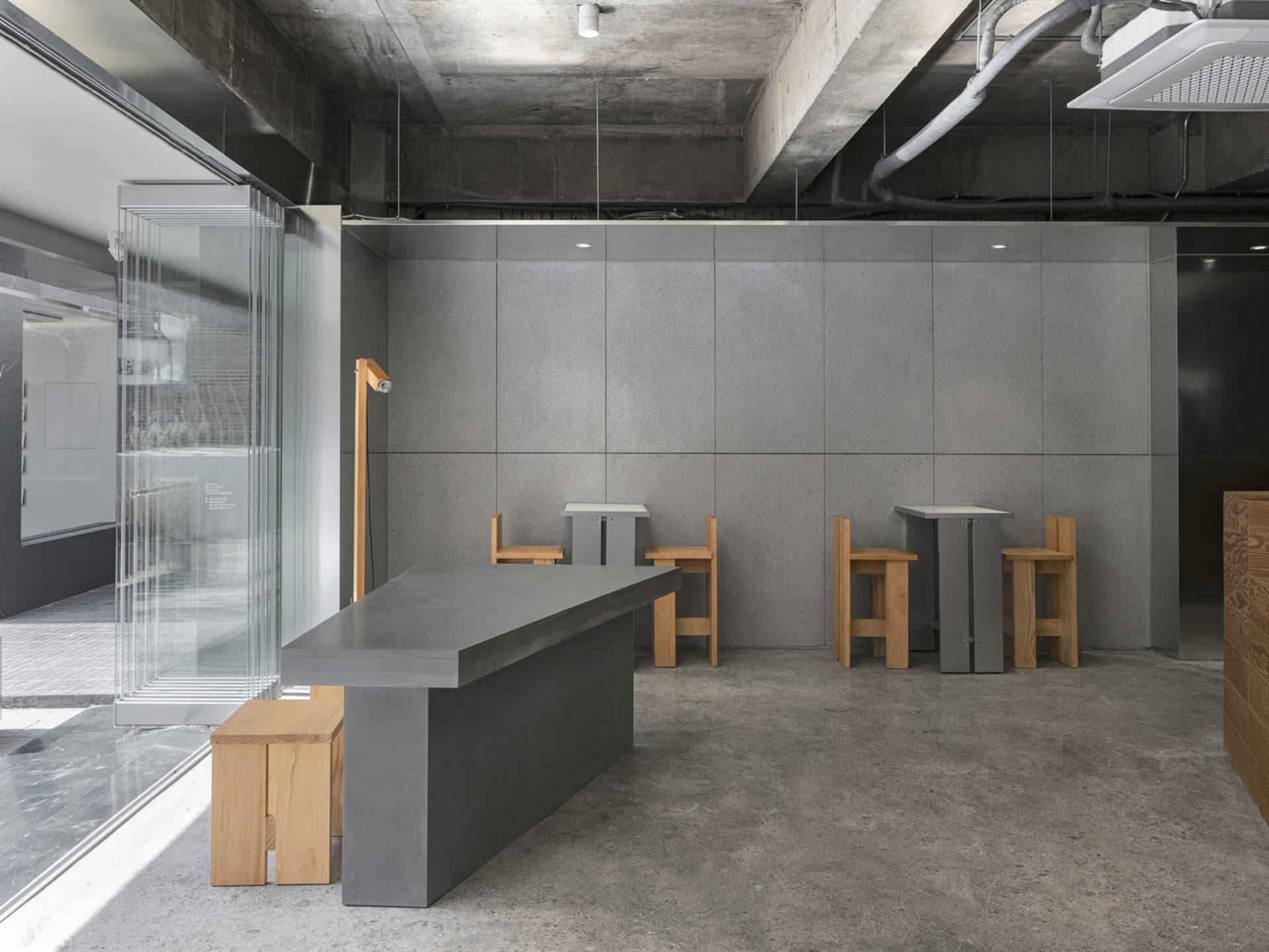 Modern restaurant interior with gray walls, wooden furniture, and a minimalist atmosphere