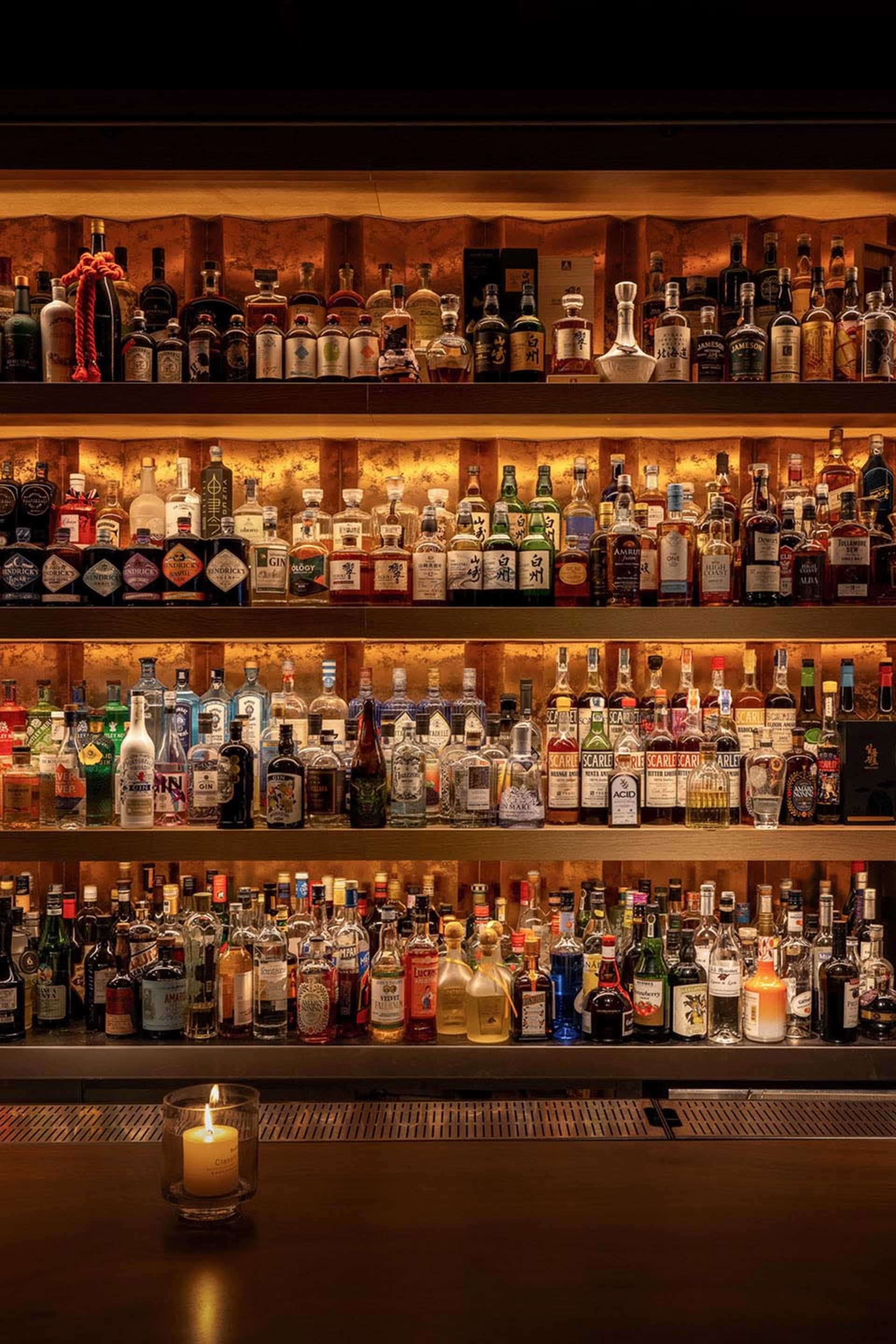 A bar area with wooden shelves displaying a collection of liquor bottles in a visually appealing arrangement, creating a warm and inviting atmosphere
