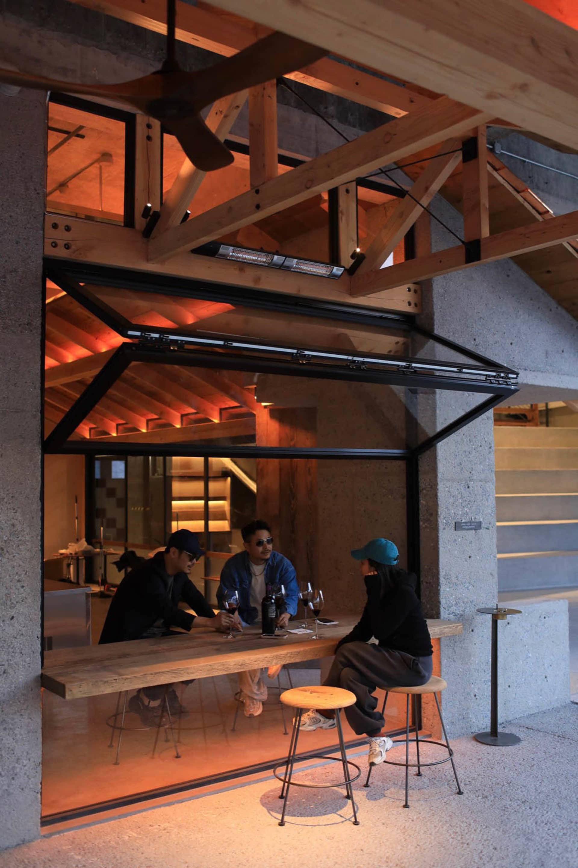 A warm and inviting restaurant setting with people seated around a dining table, enjoying food and drinks, accompanied by a dog