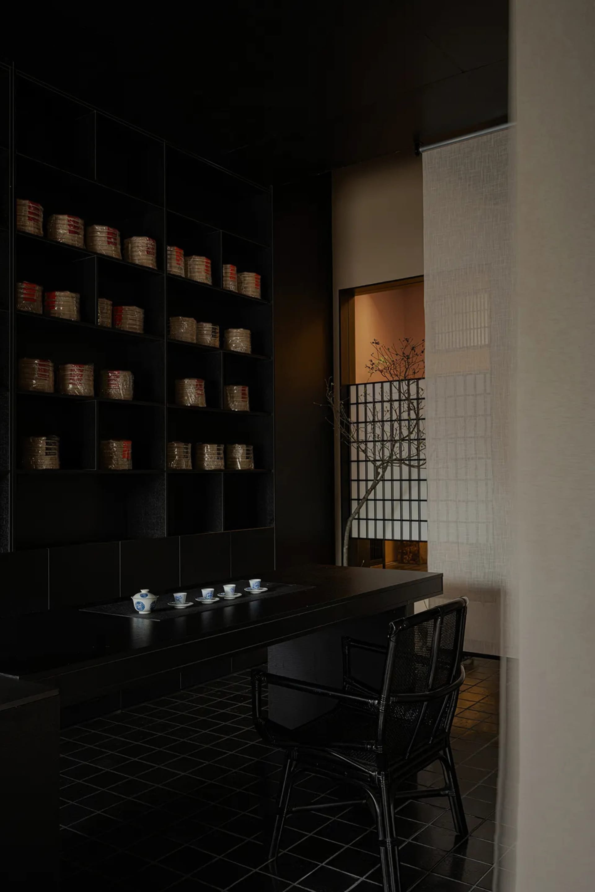 A simple Asian-style dining area with a black table, two chairs, and a cozy atmosphere