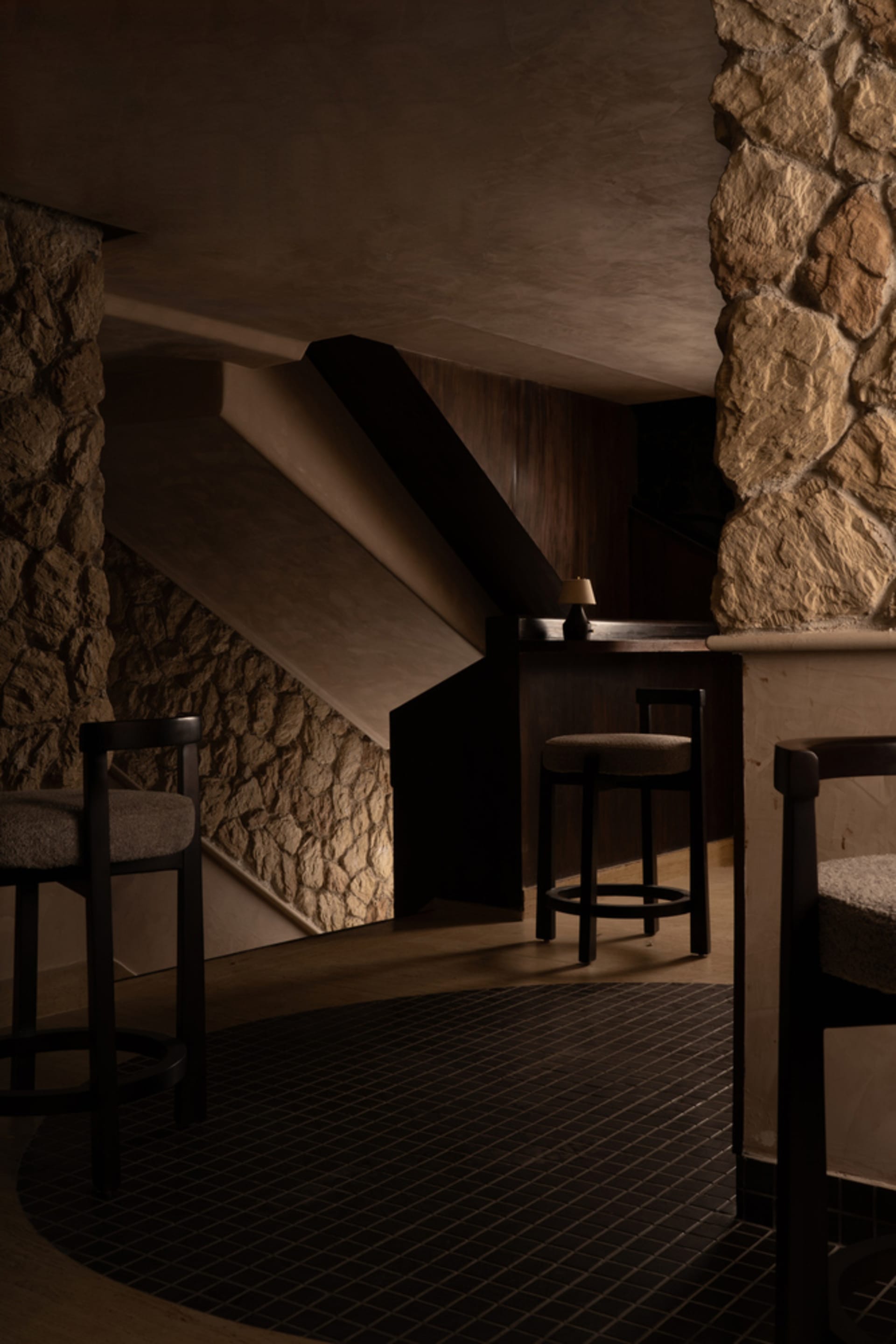 Cozy bar area with a stone wall, wooden countertop, and two stools, creating a warm and inviting atmosphere