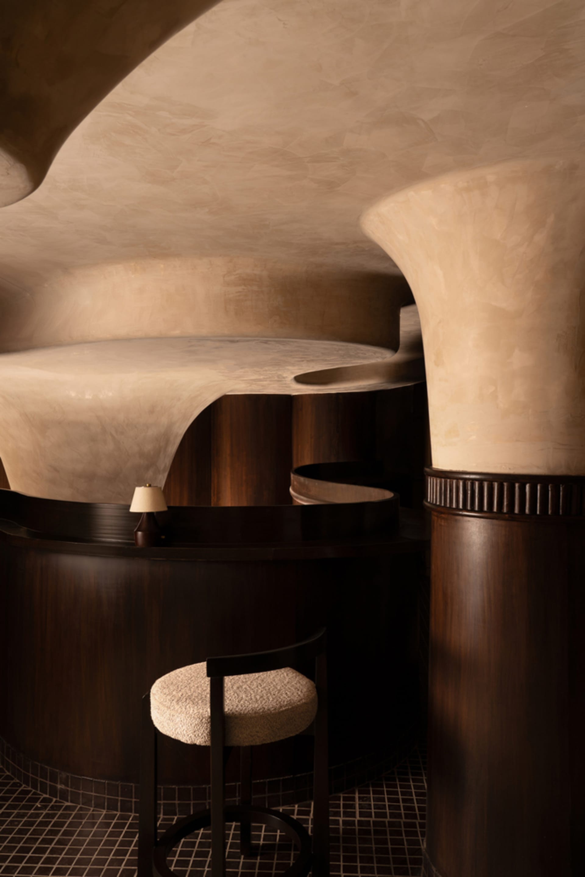 A round room with wooden panel walls, a spiral staircase, a chair, and a couch, creating a modern and cozy atmosphere