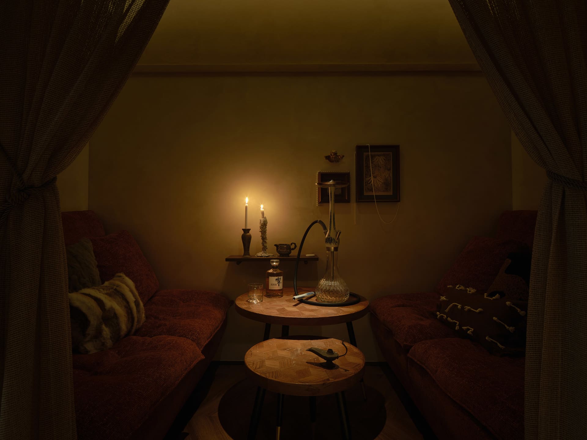 Cozy living space with two couches, chairs, and a dining table, surrounded by red walls and well-lit by natural and artificial light sources