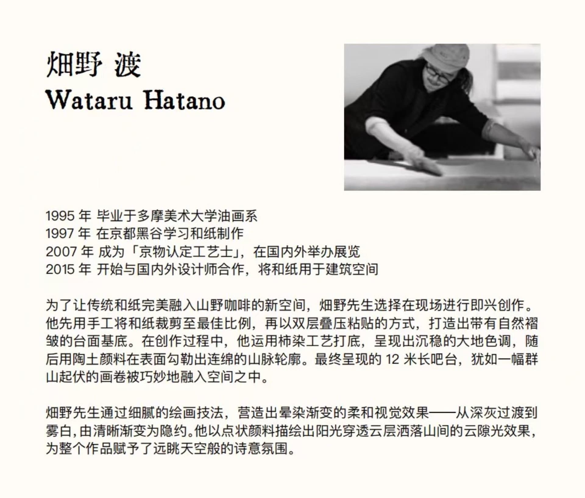 一位藝術家坐在地板上，周圍環繞書籍，在雜亂的工作室中創作一件藝術作品