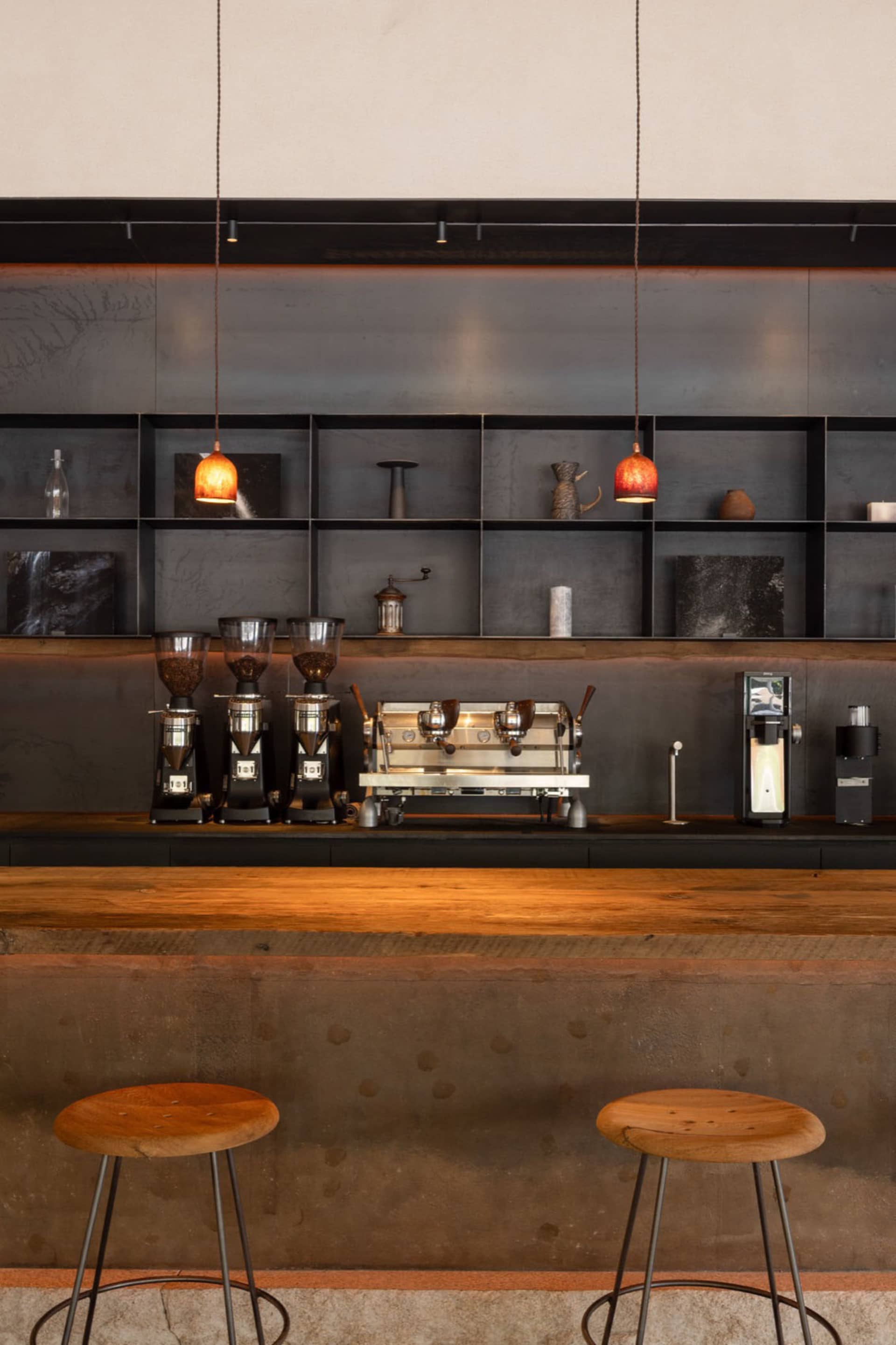 Industrial kitchen with a counter featuring espresso machines, cups, and a spoon, suggesting a functional workspace for food preparation and service