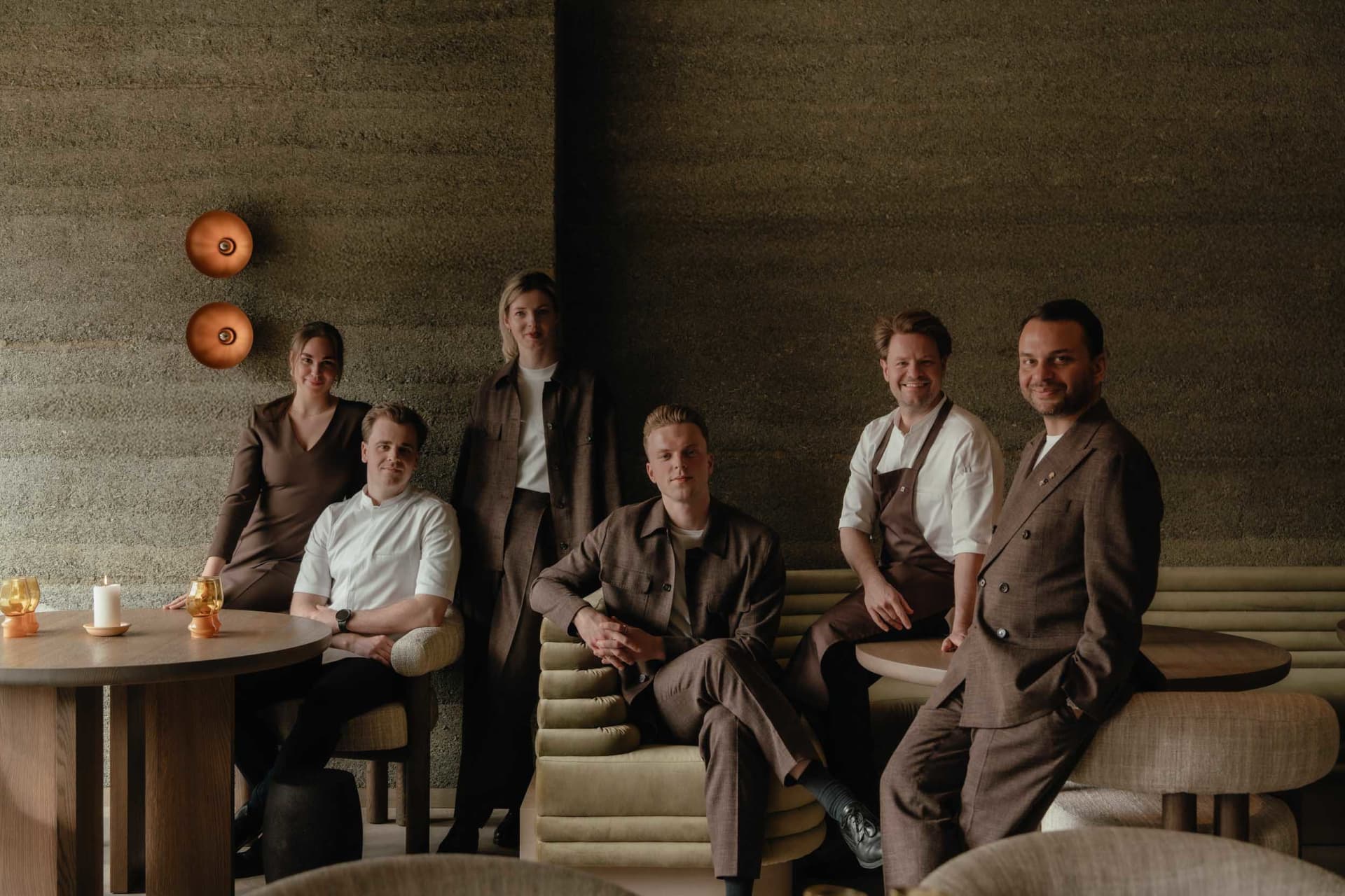 A group of people posing together in a restaurant setting with multiple chairs and a relaxed atmosphere