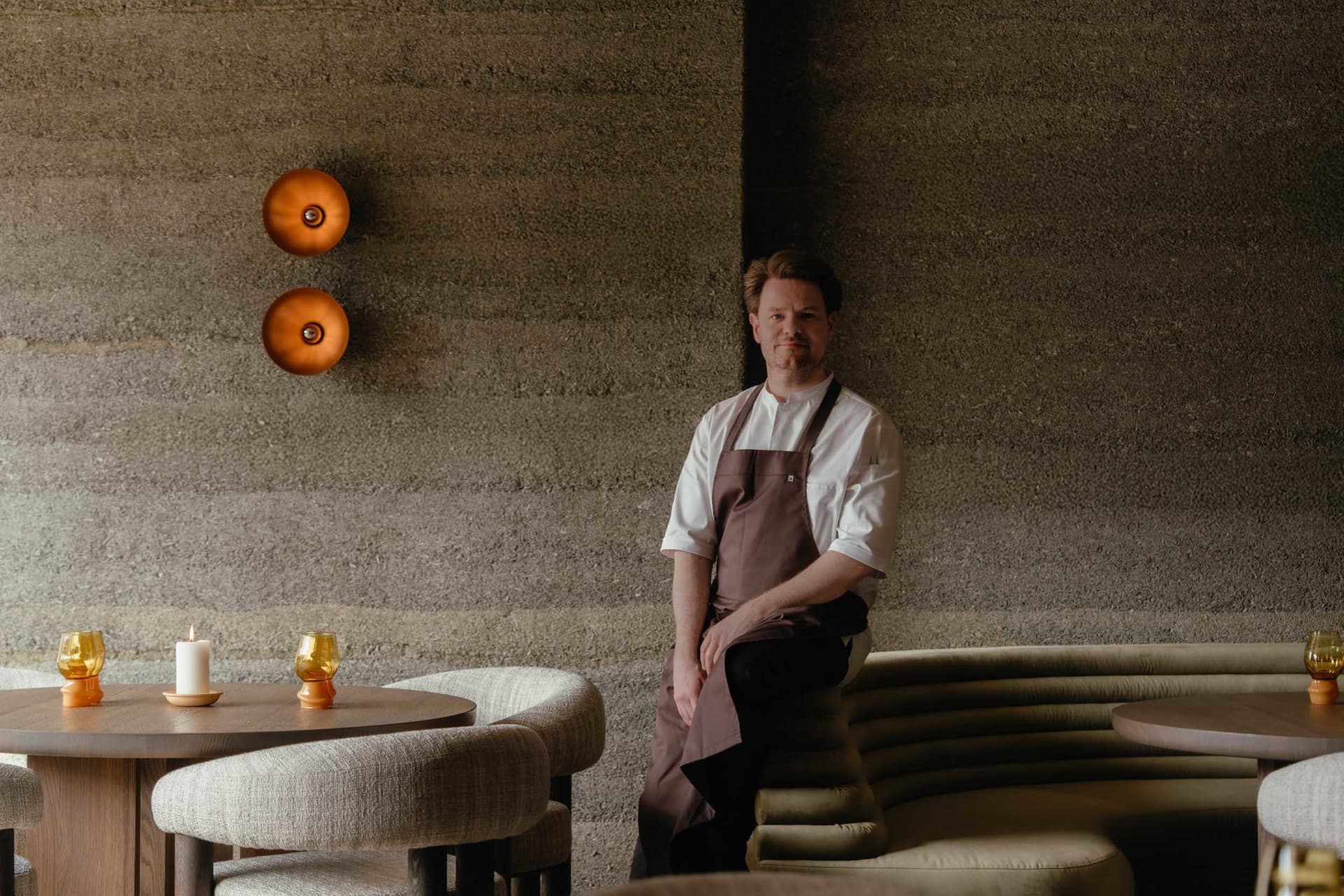 A cozy cafe interior with a stone-patterned wall, a dining table, and comfortable seating for guests