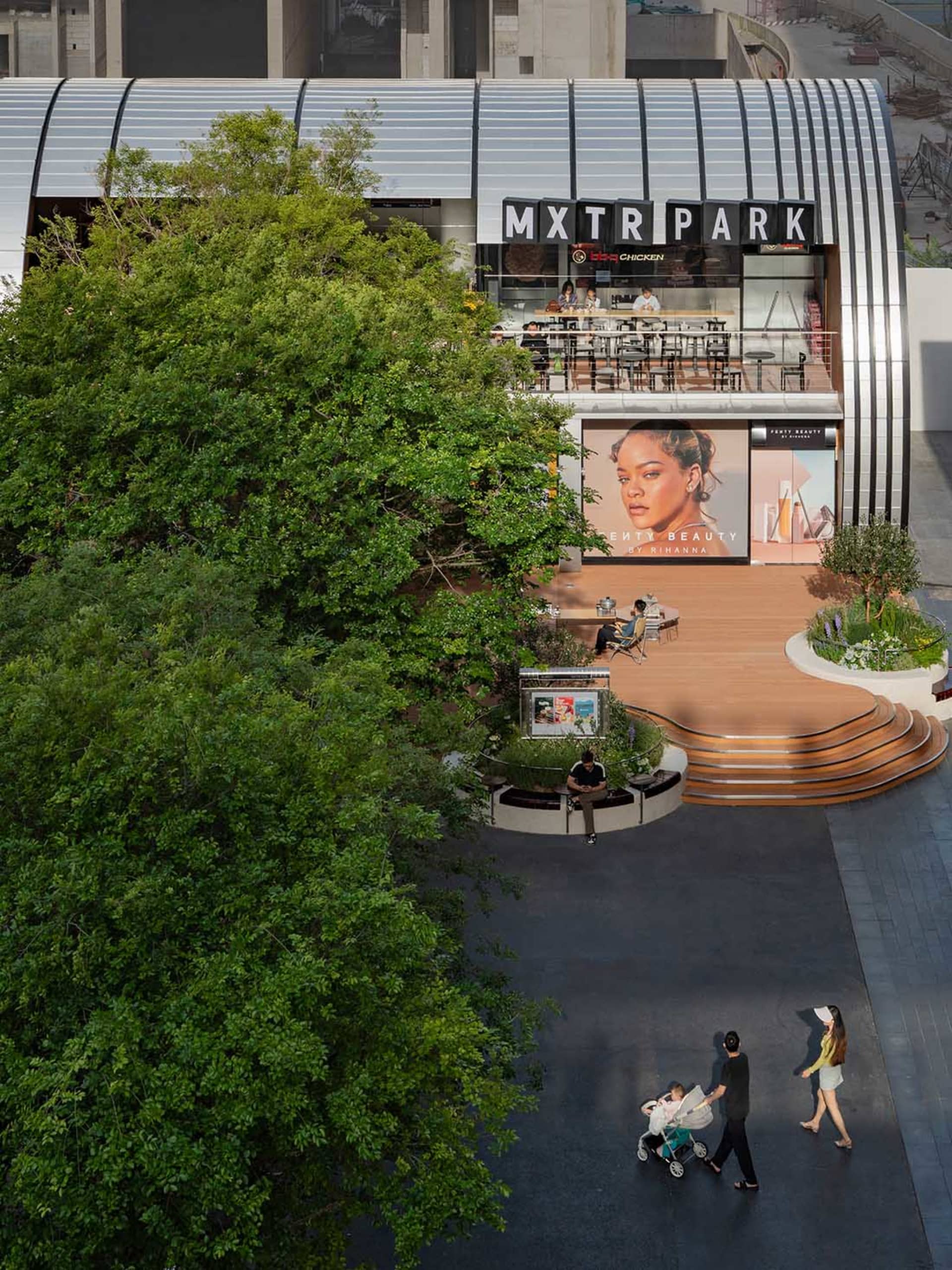 Lively outdoor shopping area with modern architecture, glass structure, and natural light, featuring people walking and engaging in activities