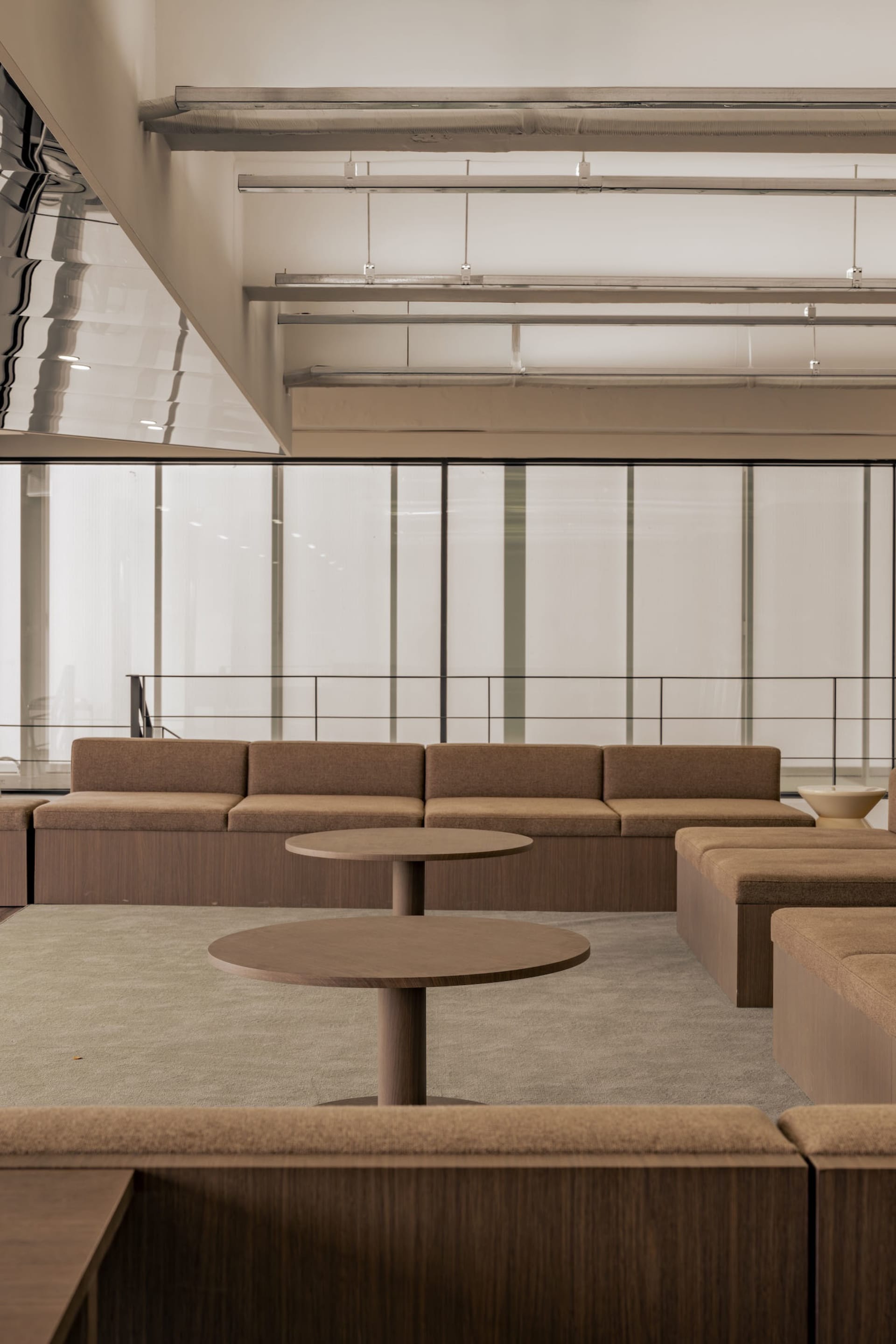 Open living space with brown couches, a chair, and natural light from a large window