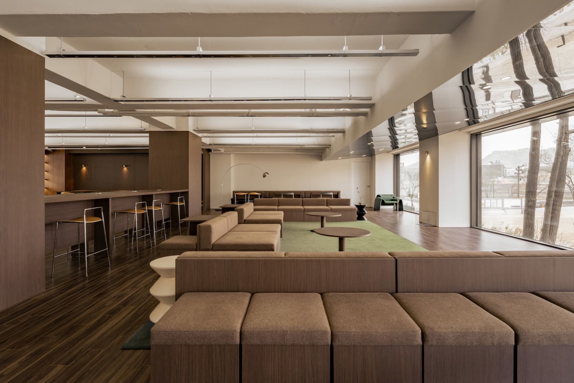 A modern living space with a large couch, chairs, dining tables, and a potted plant, creating a comfortable and inviting atmosphere