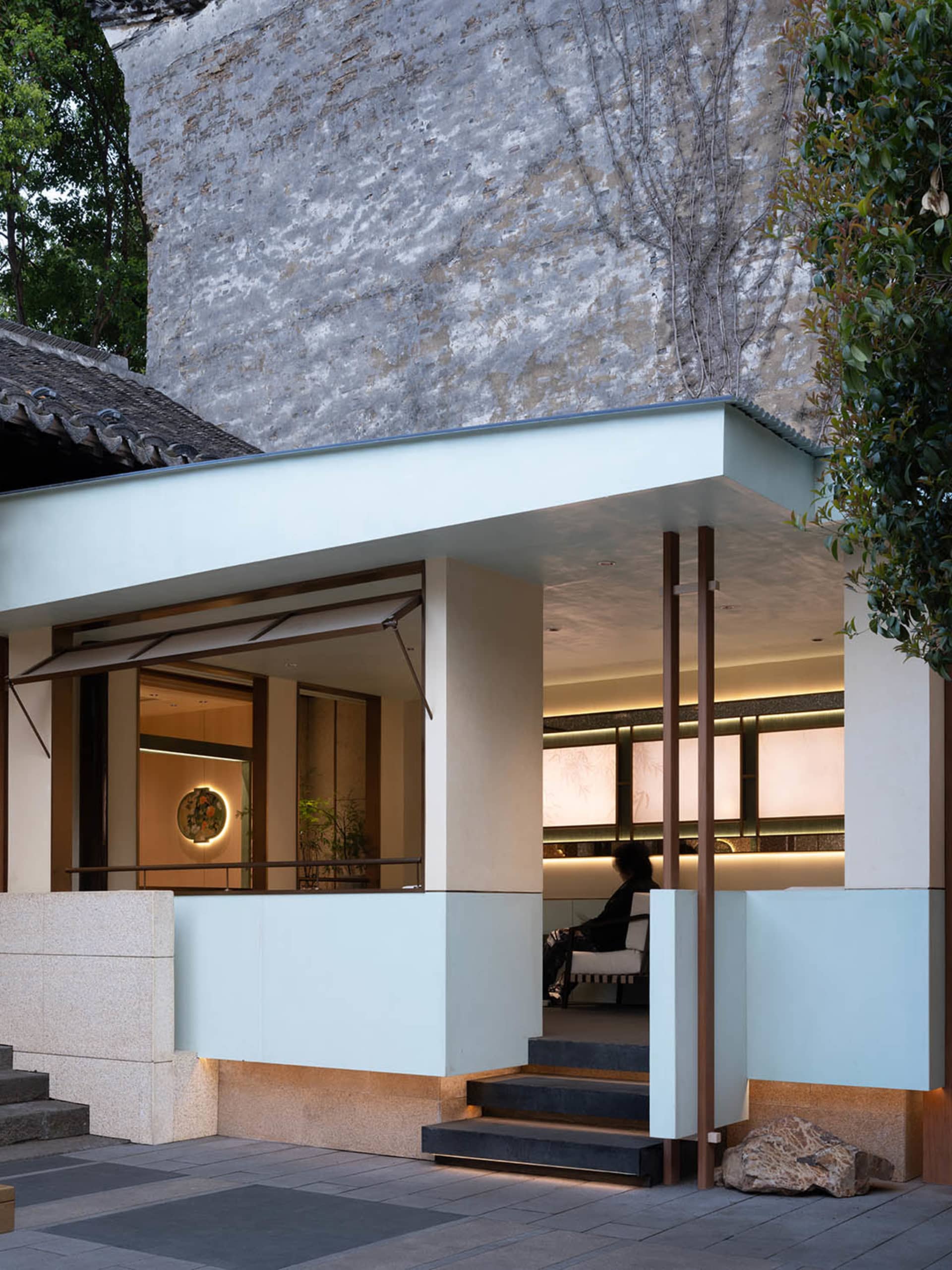 A modern traditional Asian-style house with a white exterior, featuring a spacious open area with a dining table and chairs, and two people in the scene