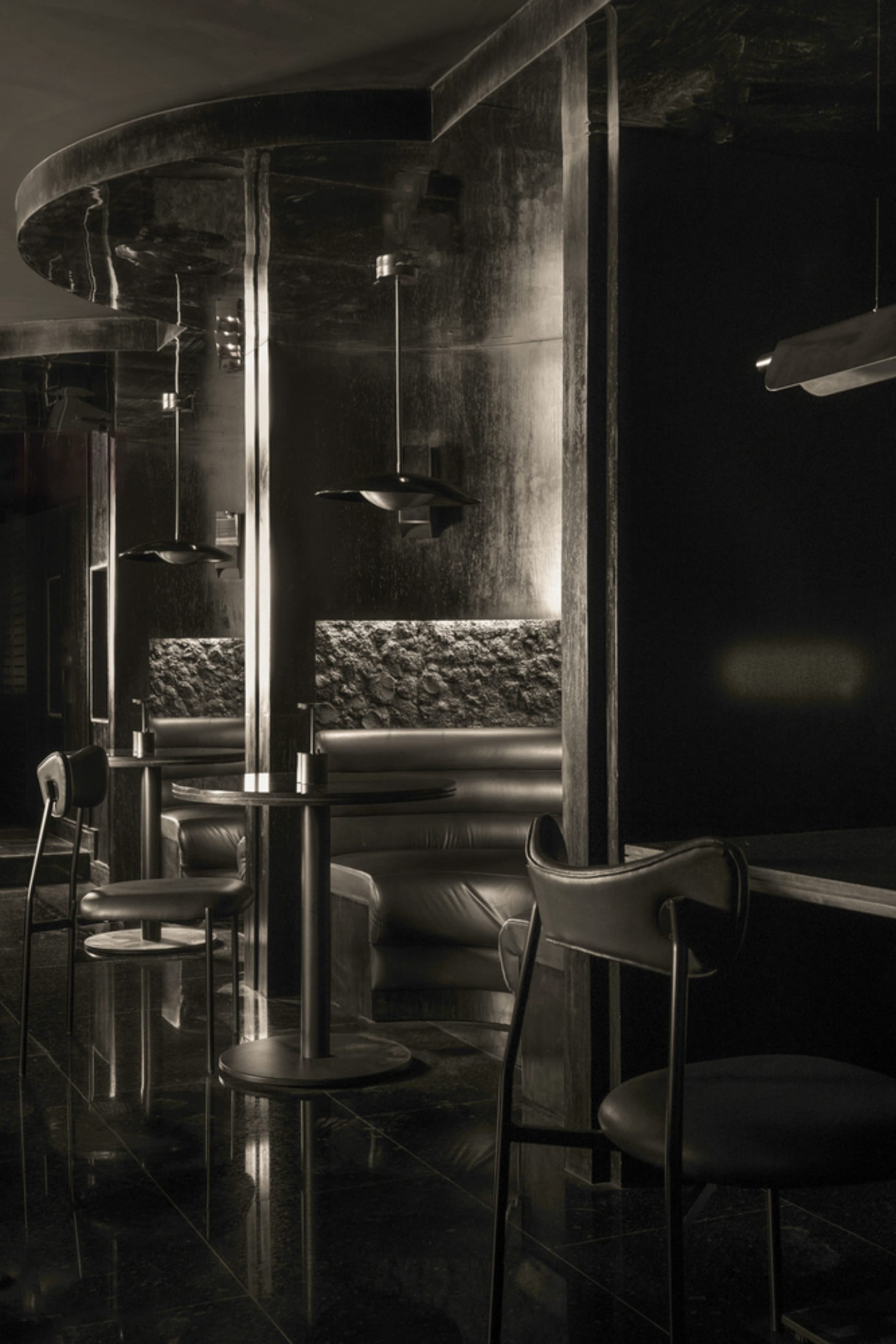 Elegant restaurant interior with multiple dining tables, chairs, a bar, and couches, featuring a black and white color scheme