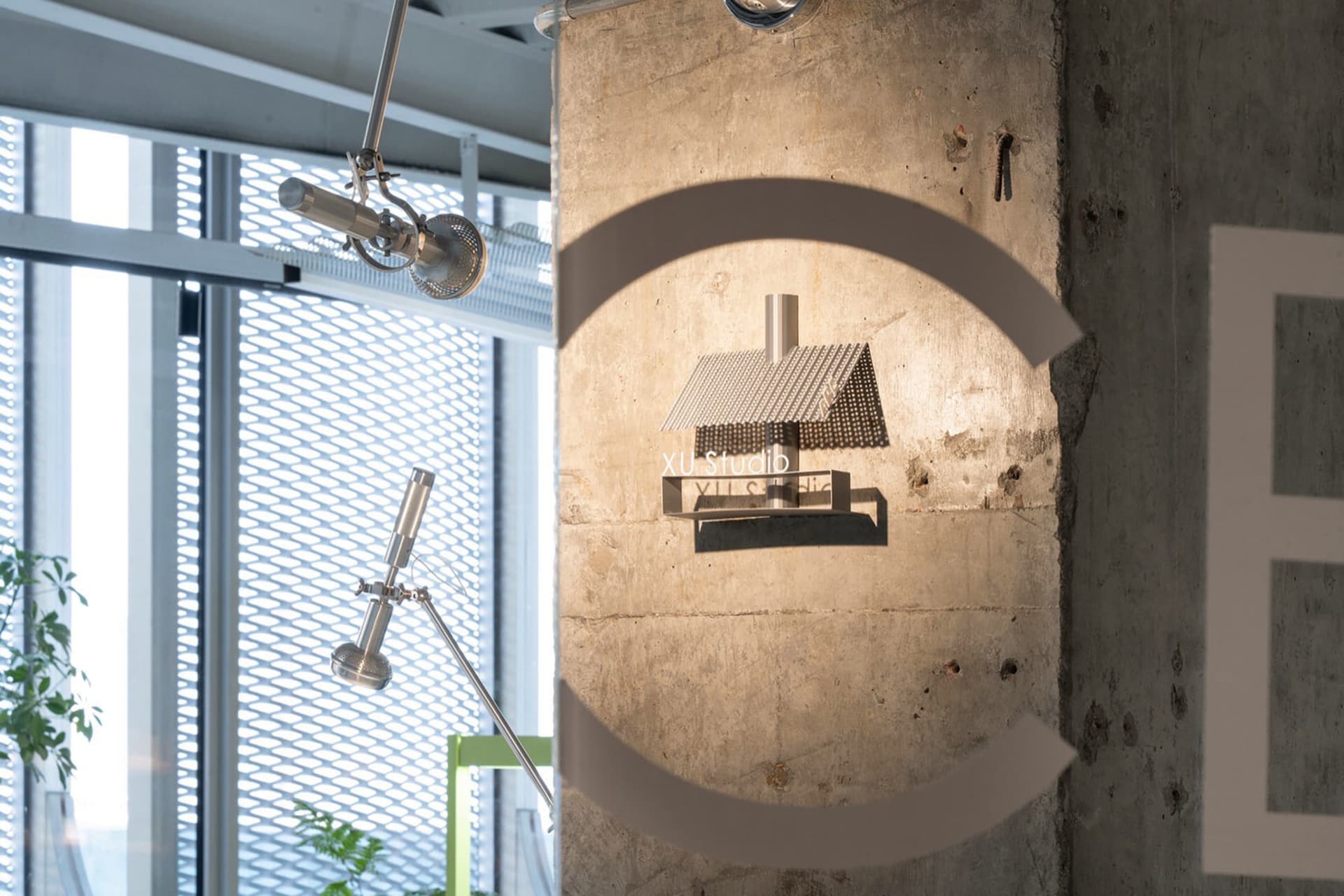 A modern house with a circular design element in front, featuring concrete and metal materials, with gray and white colors, and bright and airy lighting from above
