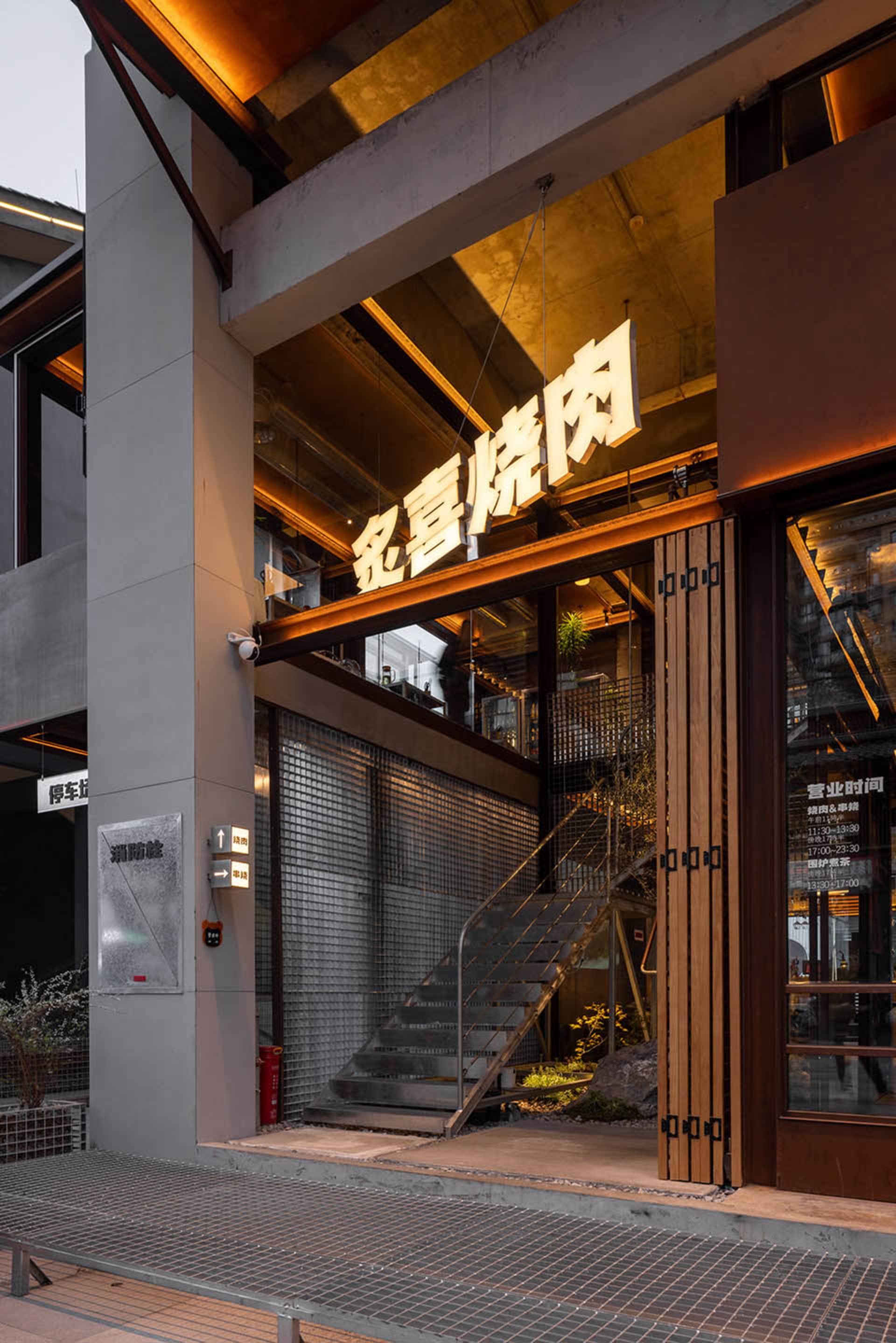 A modern Asian restaurant with a wooden staircase, potted plants, and a warm inviting ambiance