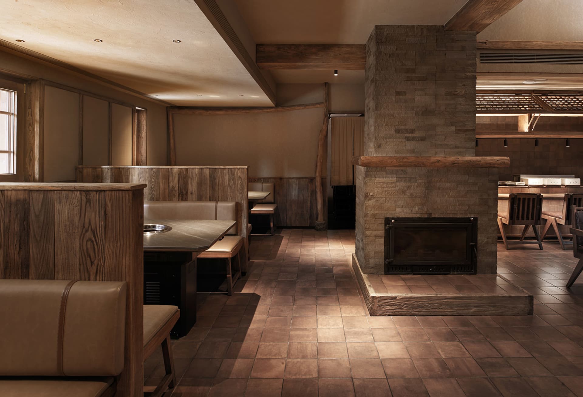 Cozy restaurant or bar space with wooden floors, brick walls, stone fireplaces, and multiple dining tables and chairs