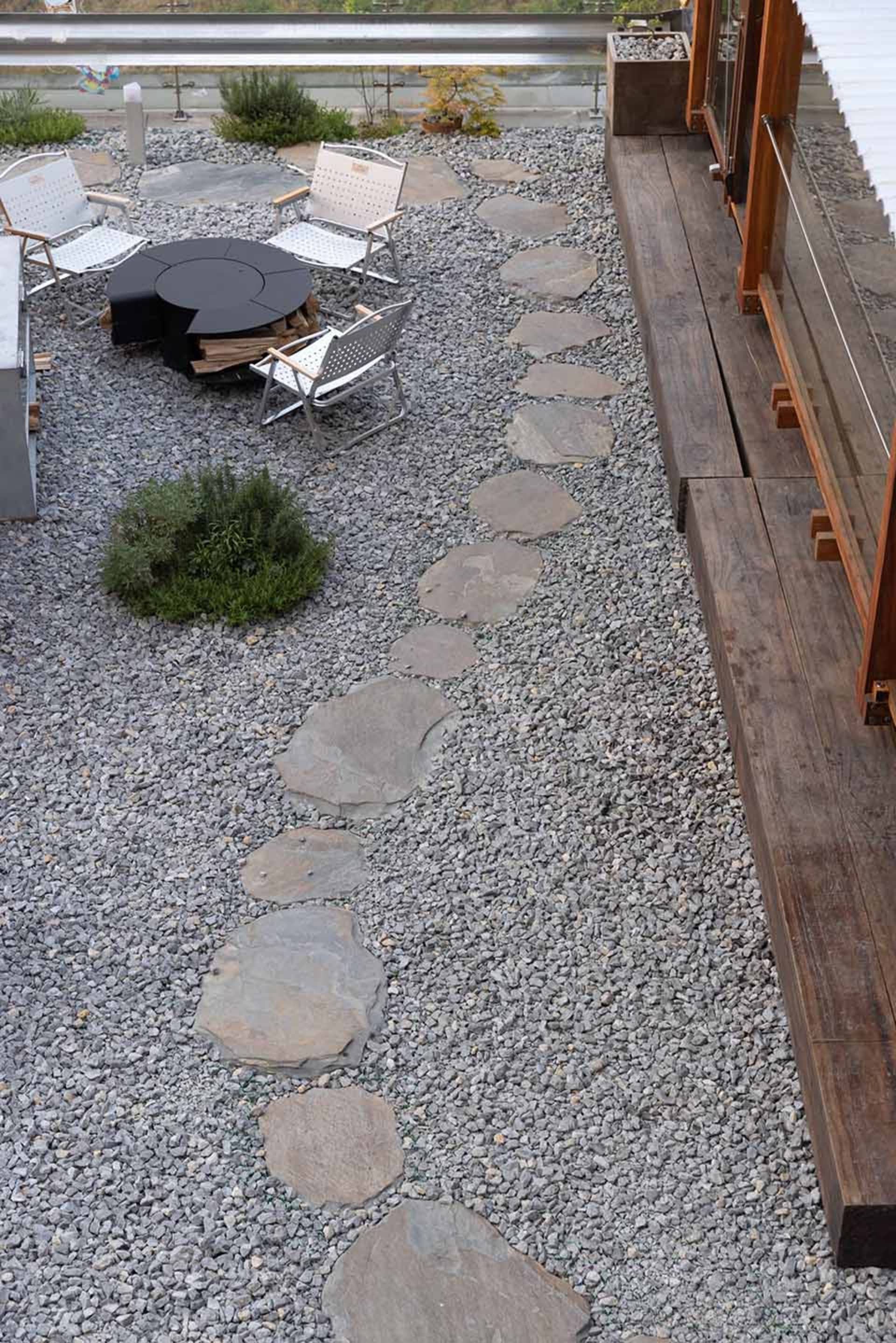 A stone walkway leads to a dining table surrounded by chairs in a relaxed outdoor seating area