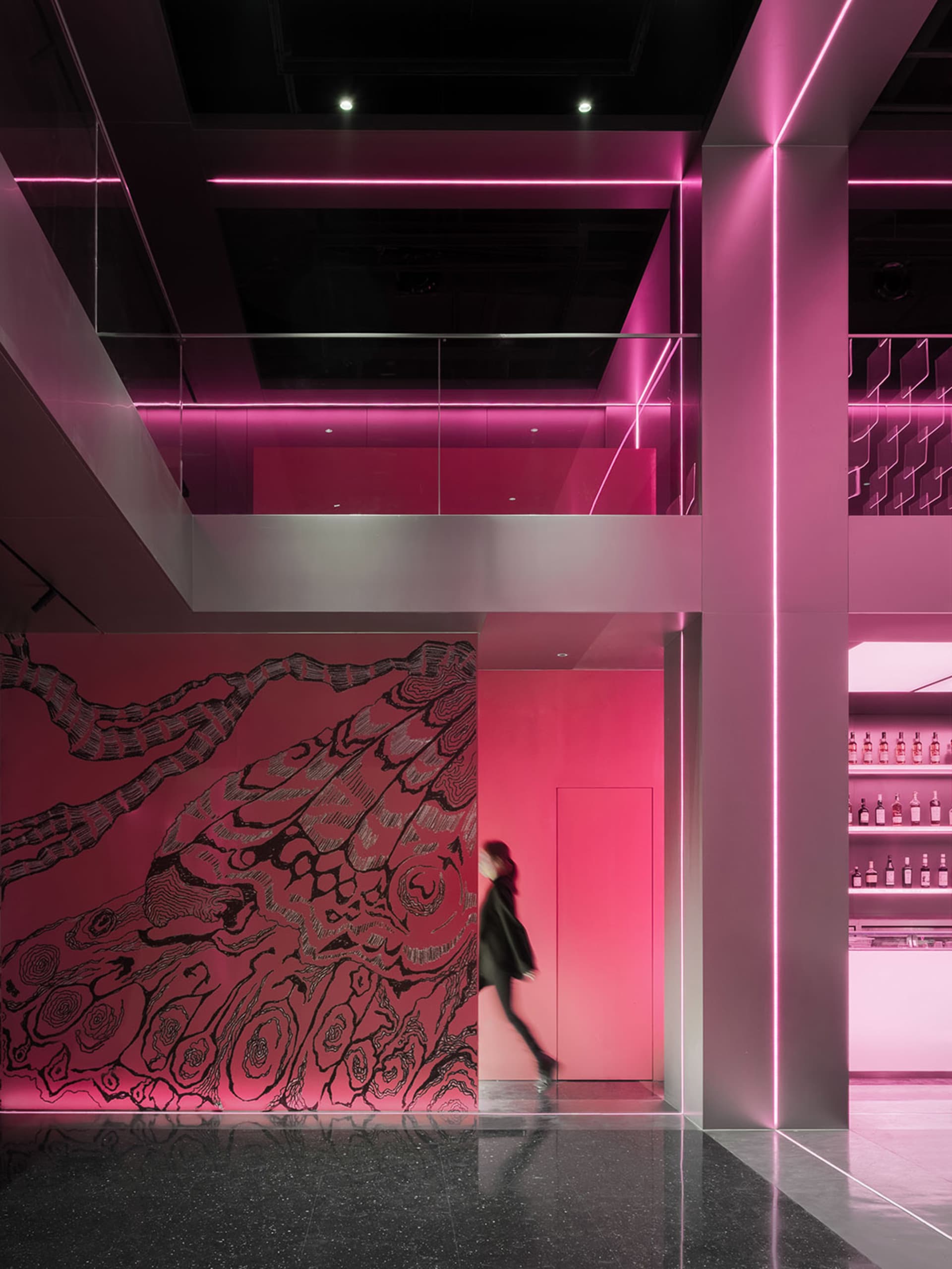 A modern interior space with pink walls and floors, featuring bottles and a creative atmosphere