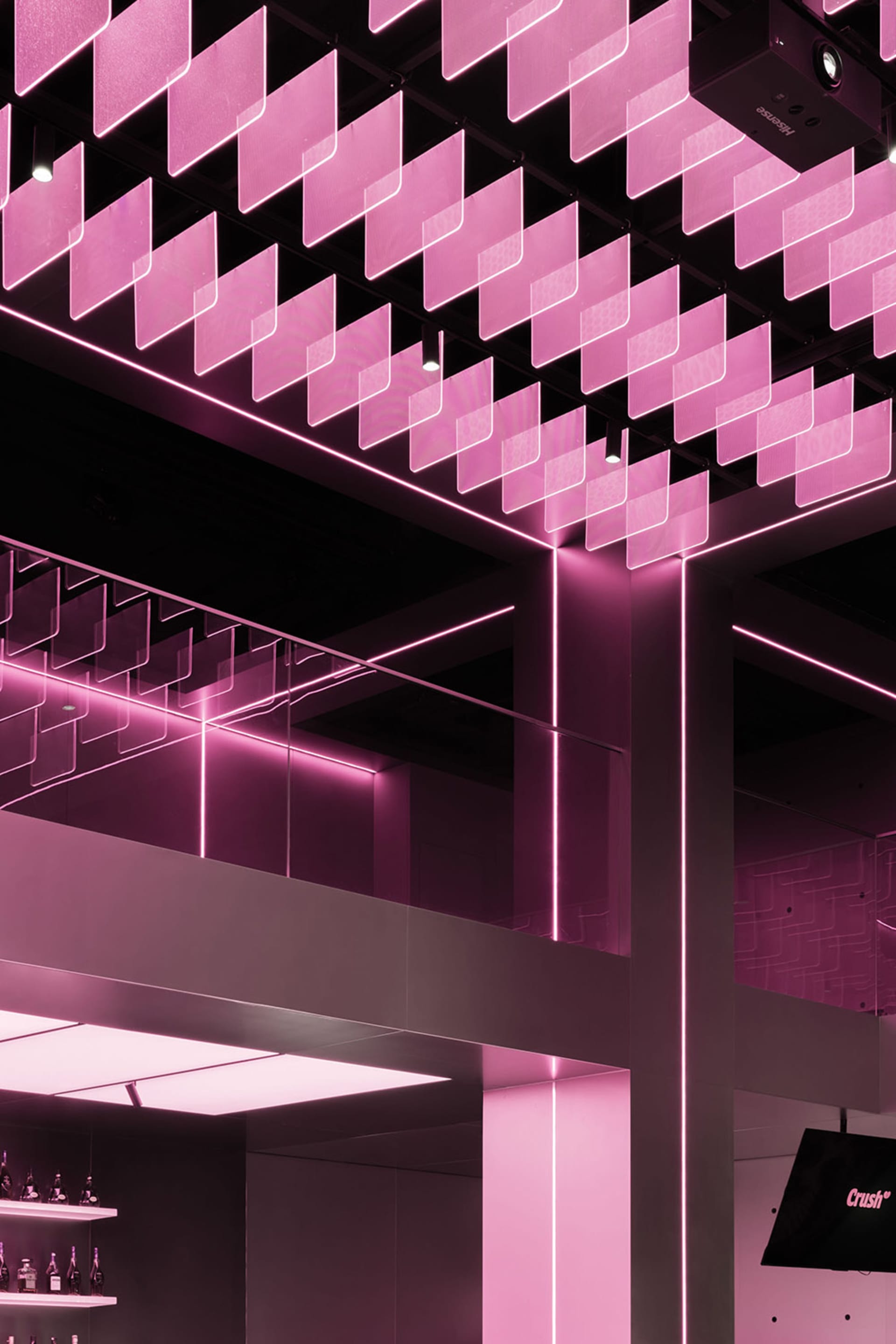 A brightly lit lobby with pink walls and ceiling, featuring neon lights and multiple staircases