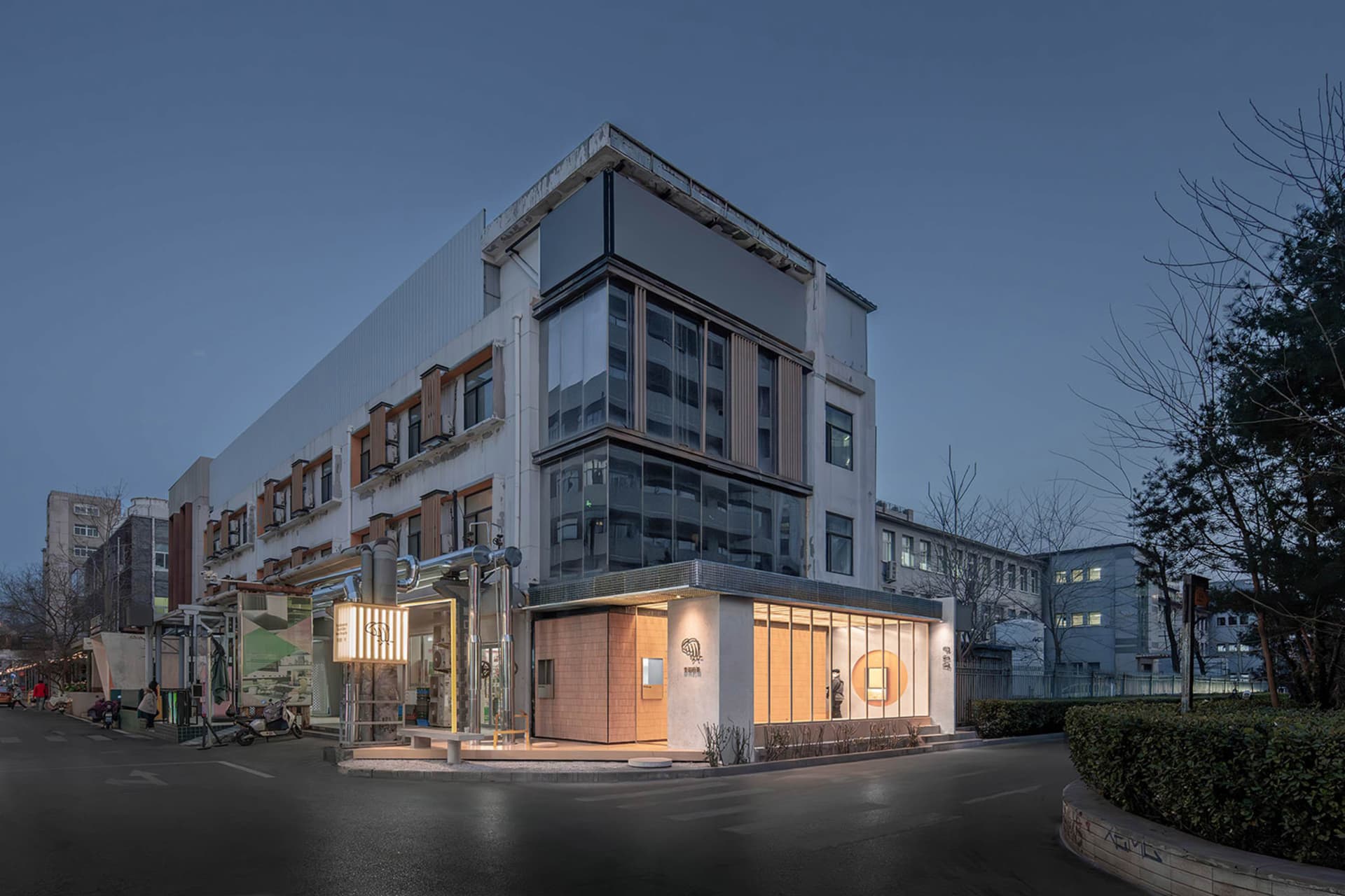 A large building with a mix of modern architectural styles, featuring glass panels and sleek lines, set in a contemporary urban context