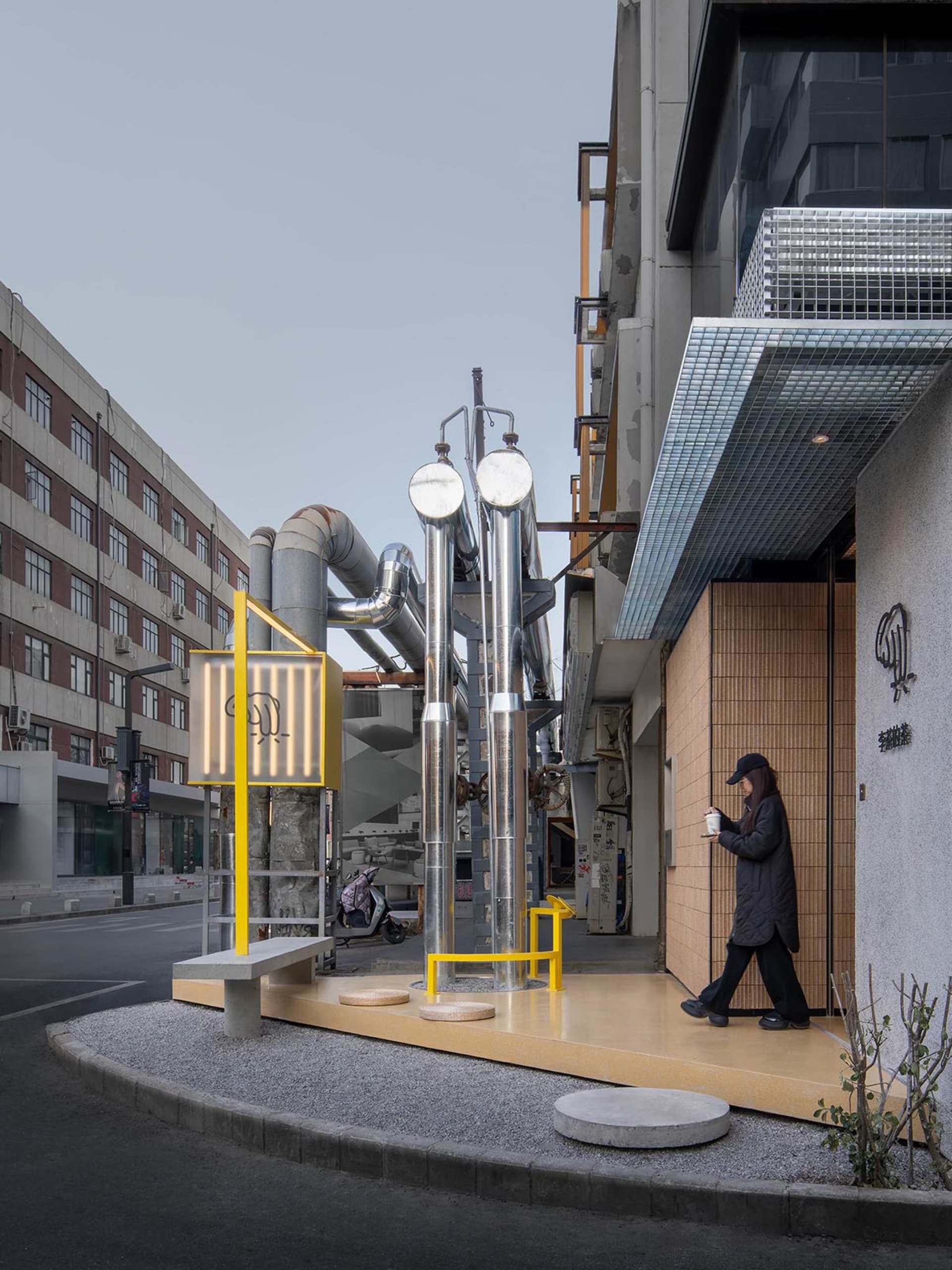 城市街景，包含建築物、長椅，以及一位女子走過，營造休閒日常氛圍
