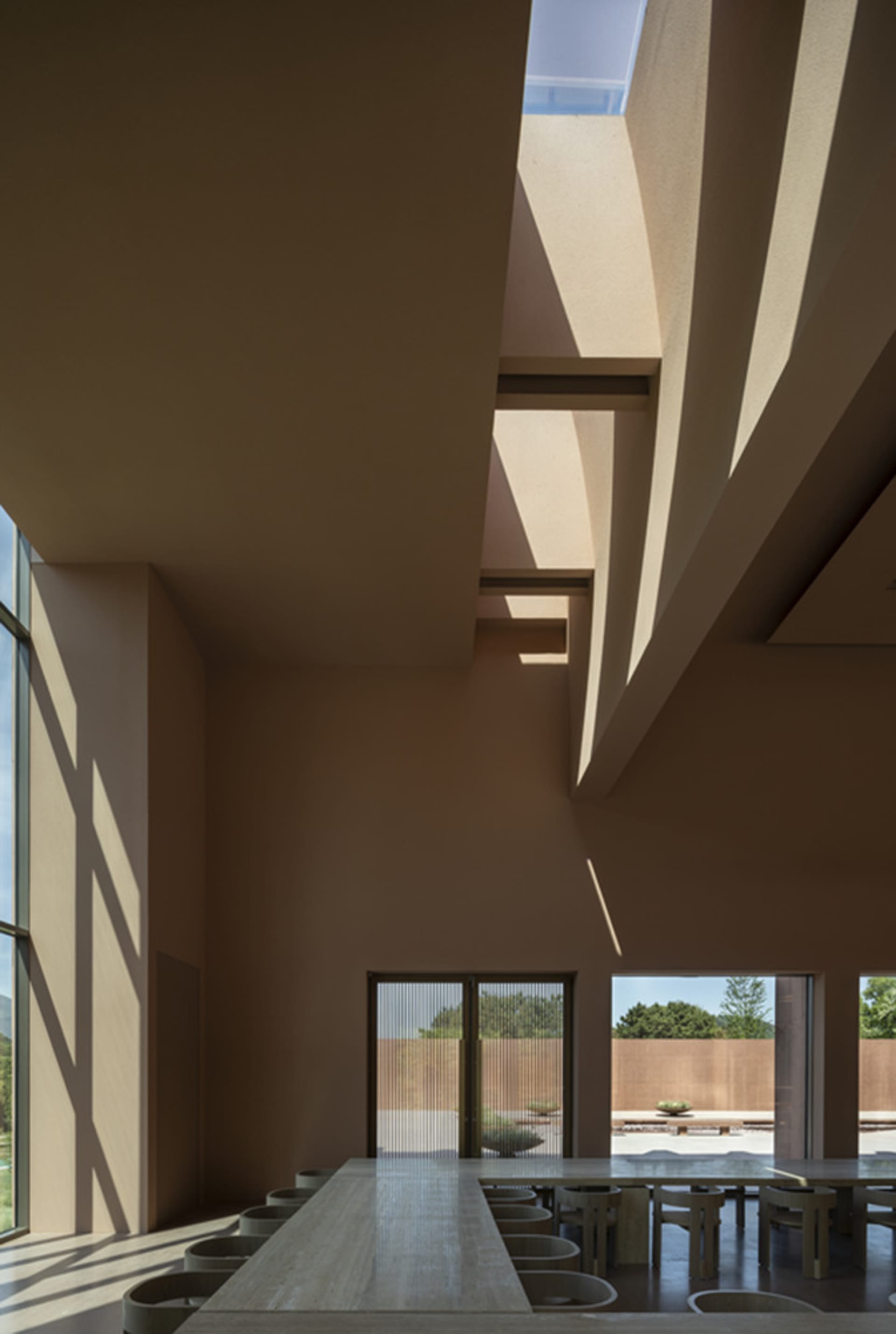 A large open space with high ceilings, a skylight, concrete walls, and two windows, giving a modern and industrial feel